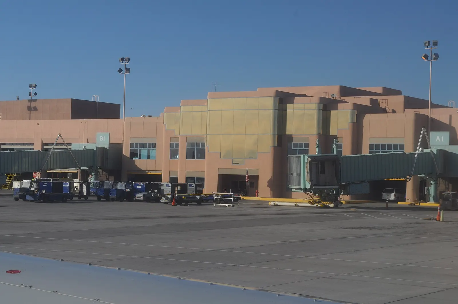 Pueblo Revival passenger terminal at Albuquerque International Sunport seen from the tarmac, with jet bridges along the facade.