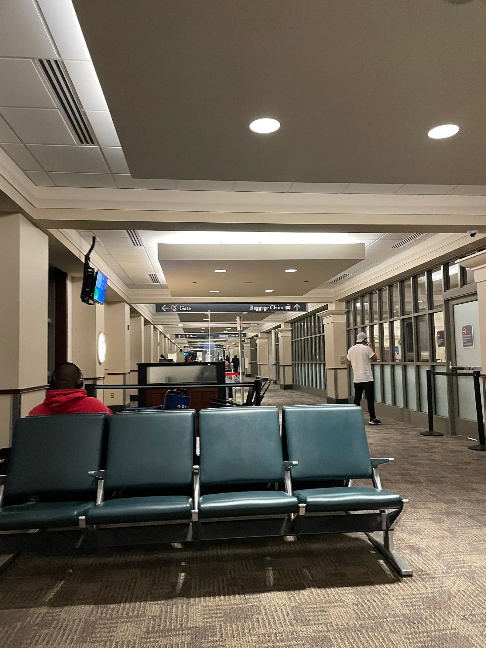 Airside corridor with a four-seat bench and overhead signs for Gate 3 and Baggage Claim at Alexandria International Airport.