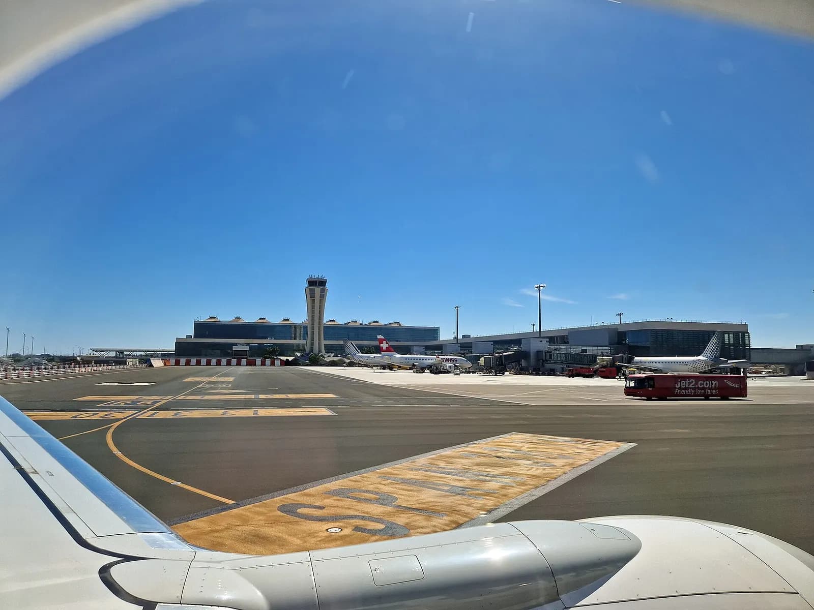 A contemporary 2023 scene inside Málaga Airport shows the passenger concourse with signage, seating, and travelers during normal operations.