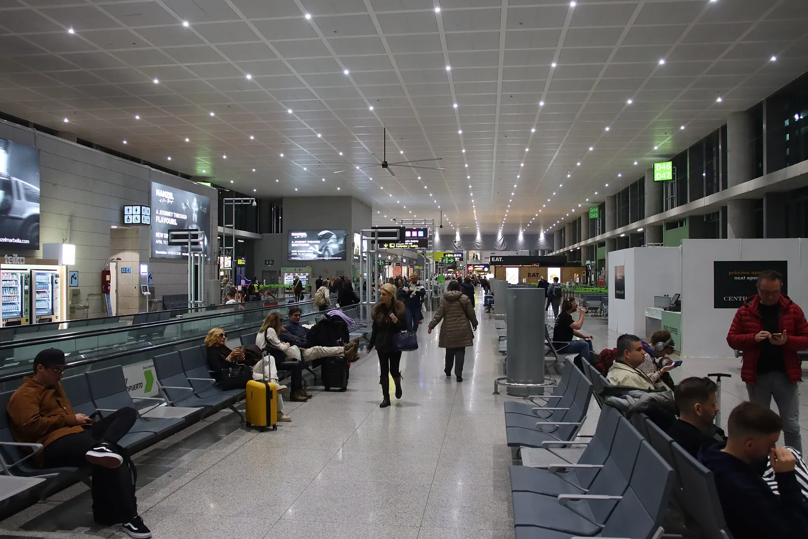 A wide 2023 view of Málaga Airport showing updated terminal structures, passenger areas, and the surrounding Costa del Sol landscape.