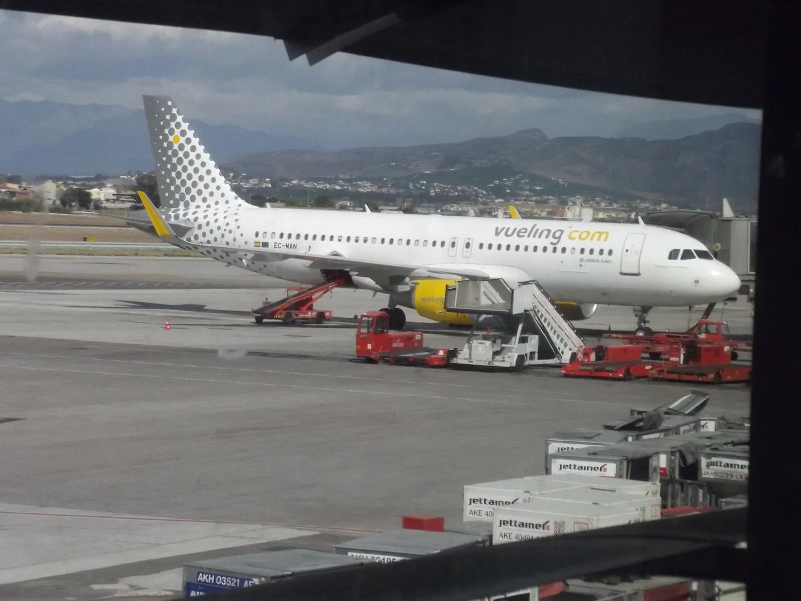 Passengers wait in the Terminal 3 departure lounge while aircraft stand at gates visible through tall windows overlooking the apron.