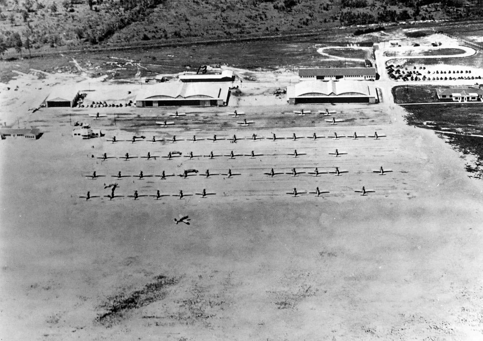 1943 flight line at Bush Field with Vultee BT-13 Valiant trainers and hangars. Historic WWII contract-school scene, not the 2007 TSA hall.