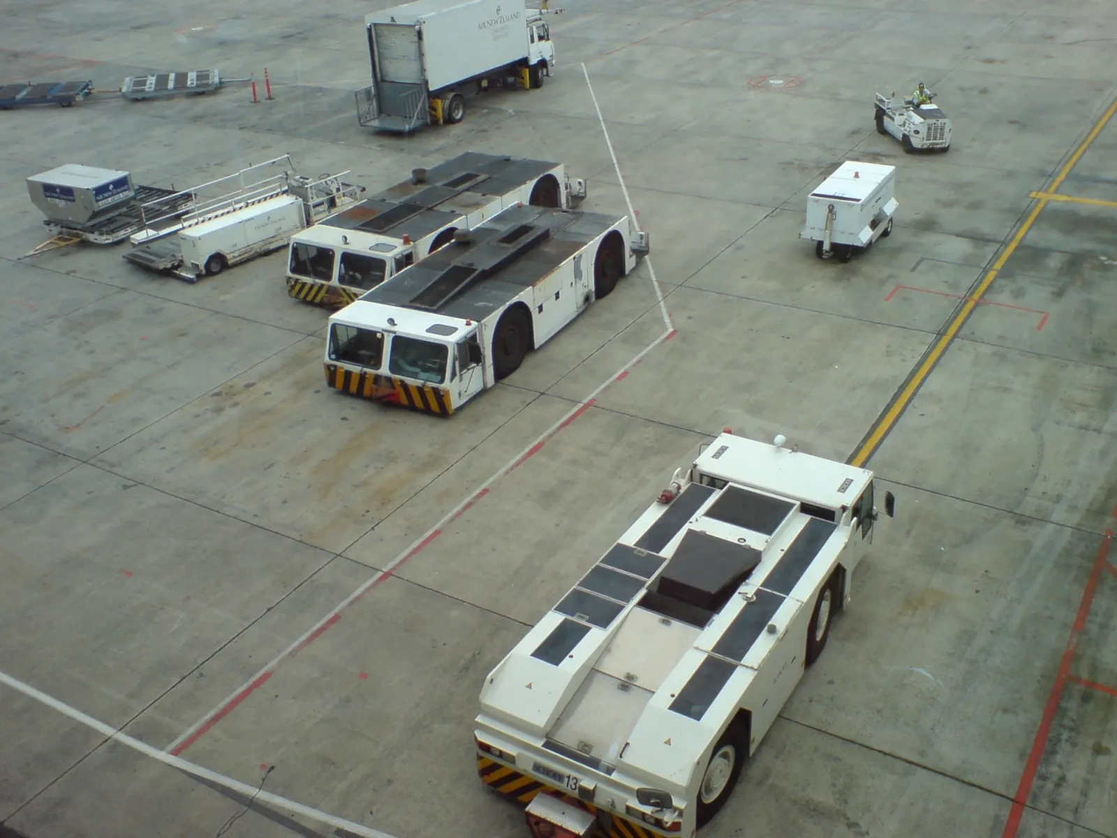 Airport vehicles at the international terminal, Auckland International Airport , Auckland , New Zealand . Viiew out of the windows of a departure lounge looking roughly southwest.