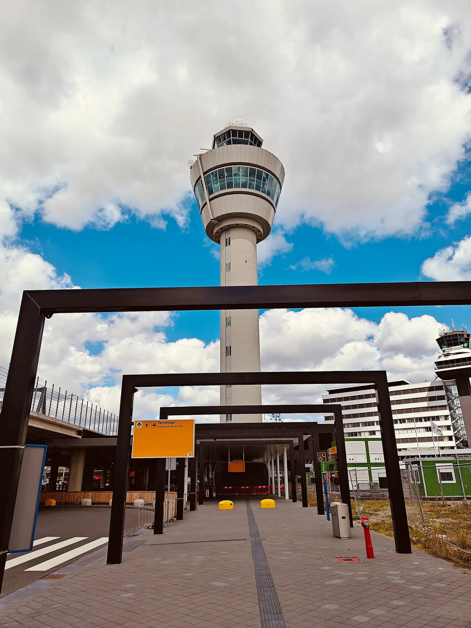 Schiphol's distinctive air traffic control tower rising above the terminal, seen from the shuttle bus area in 2024.