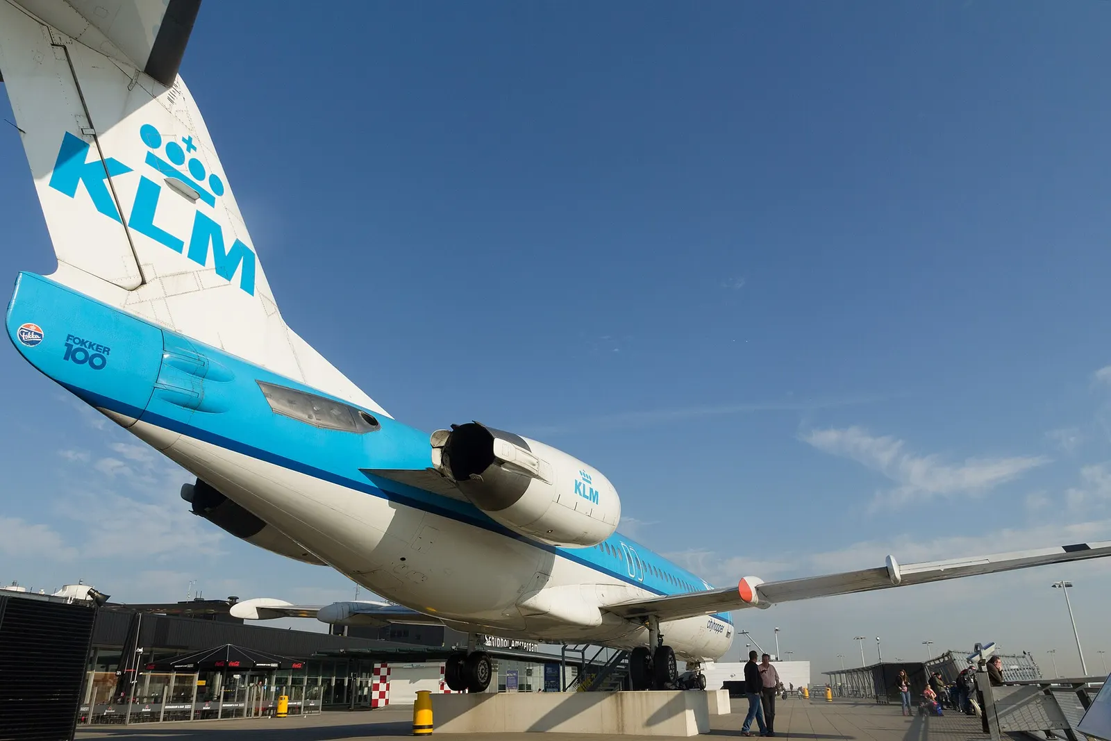A retired KLM Cityhopper Fokker 100 aircraft on permanent display at Schiphol's Panorama Terrace overlooking the apron.