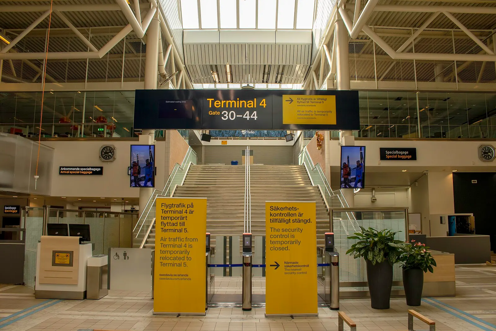 Interior of Terminal 4 showing a modern departure lounge with check-in kiosks, seating, and natural light.