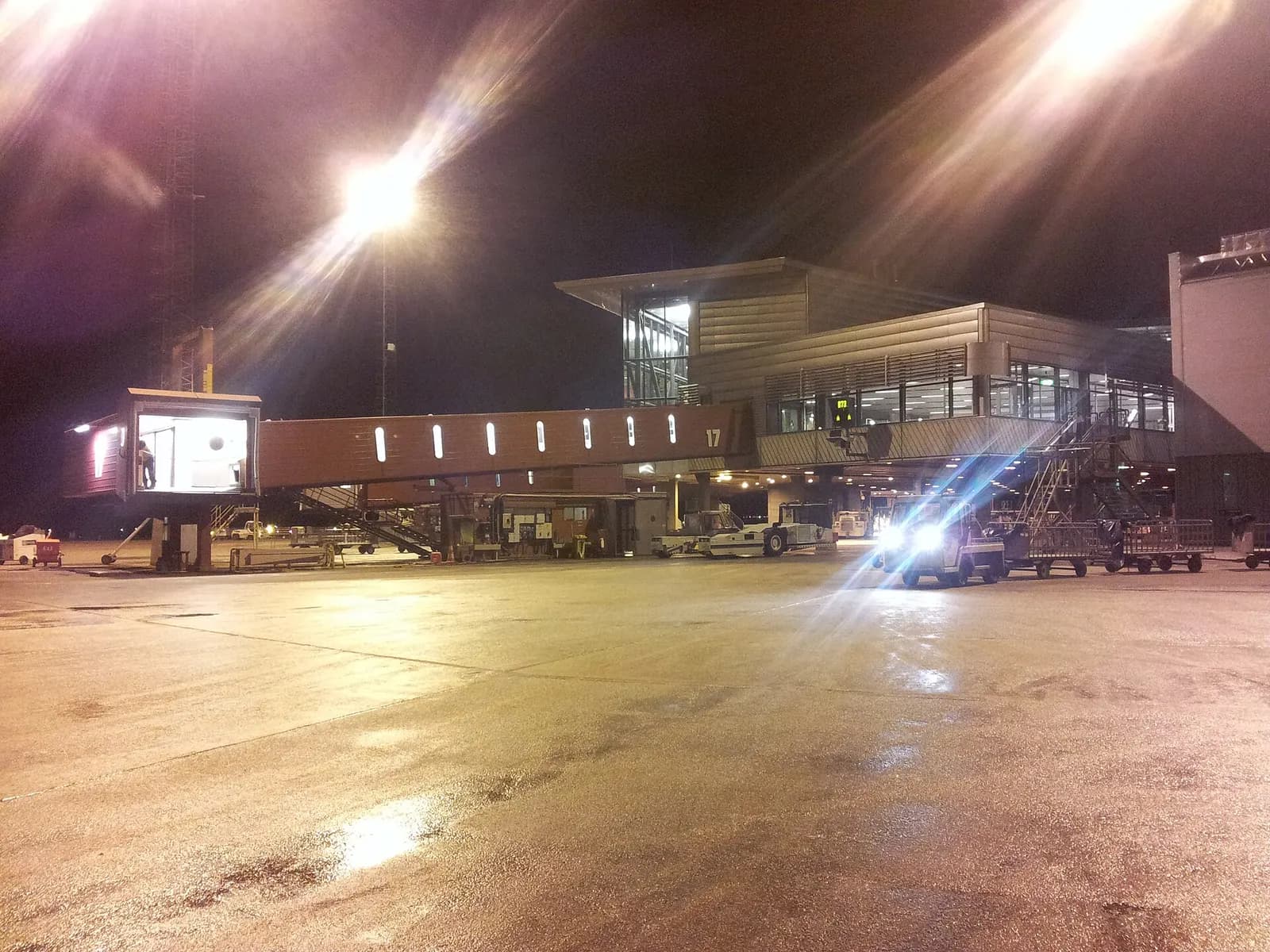 Airport gate area at Gate 17 with seating, flight information displays, and large windows overlooking the apron.