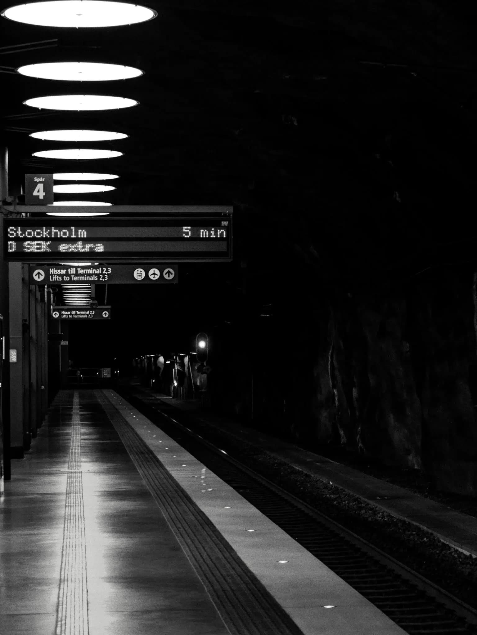 Passengers waiting on a platform at Arlanda Airport station for a train toward Stockholm.