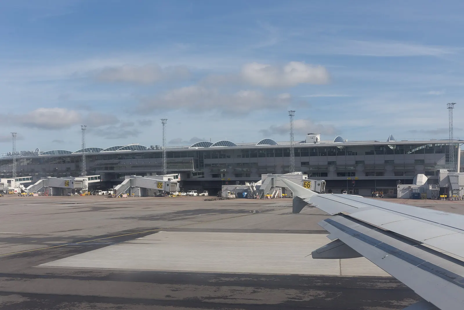 Exterior of Terminal 2 at Stockholm Arlanda Airport on a clear day, with the building facade and nearby road.