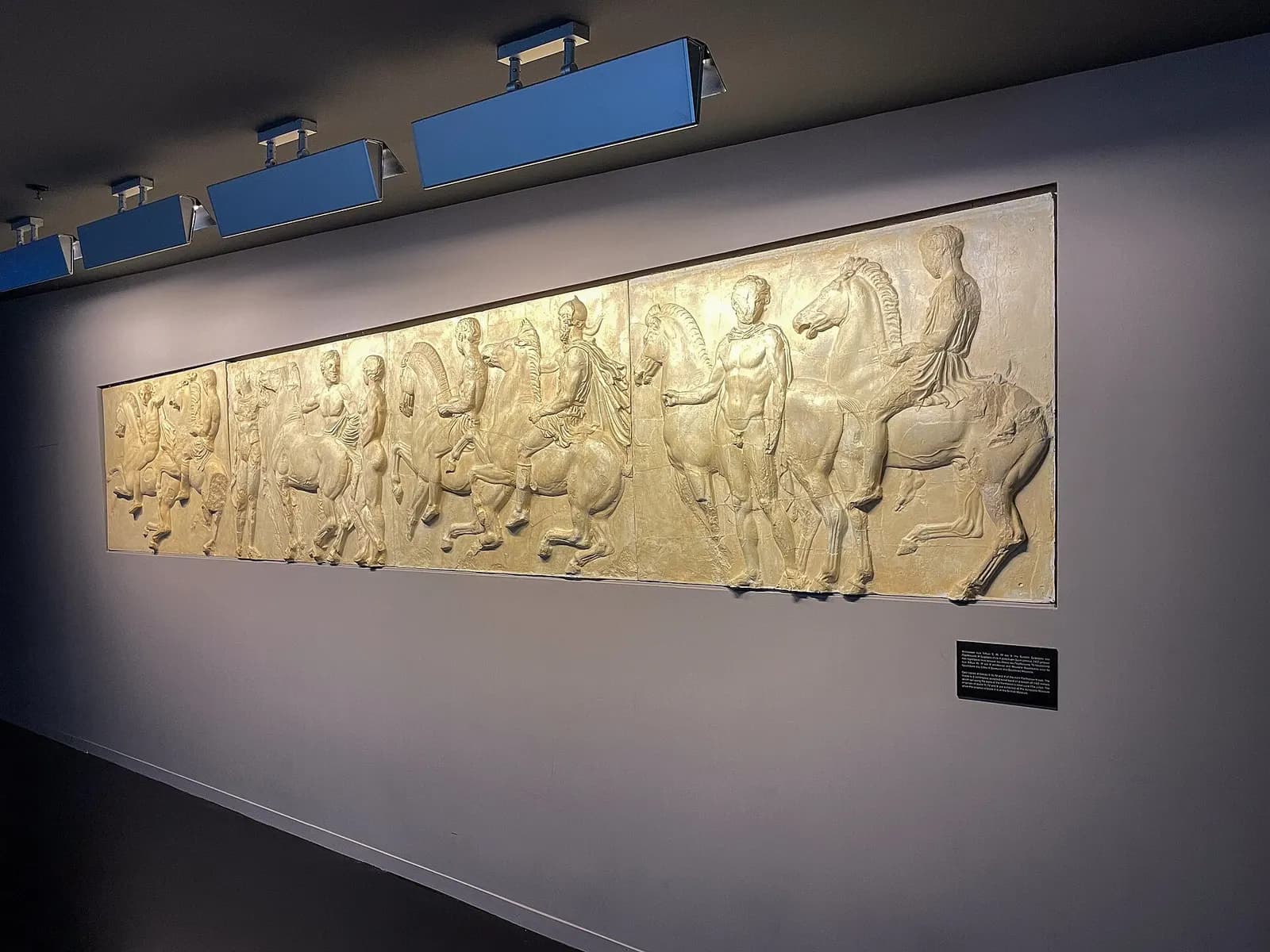 Replicas of Parthenon frieze panels displayed in the Athens International Airport archaeological collection inside the terminal.