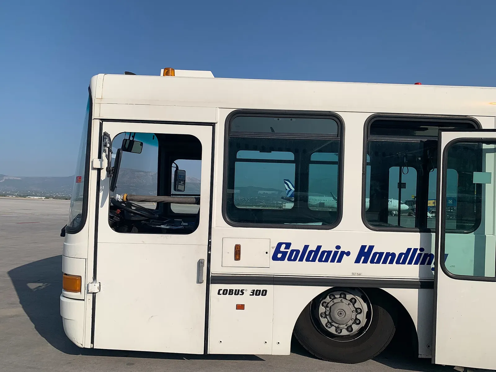 A Goldair Handling passenger shuttle bus on the apron at Athens International Airport, used to move travelers between the terminal and aircraft.
