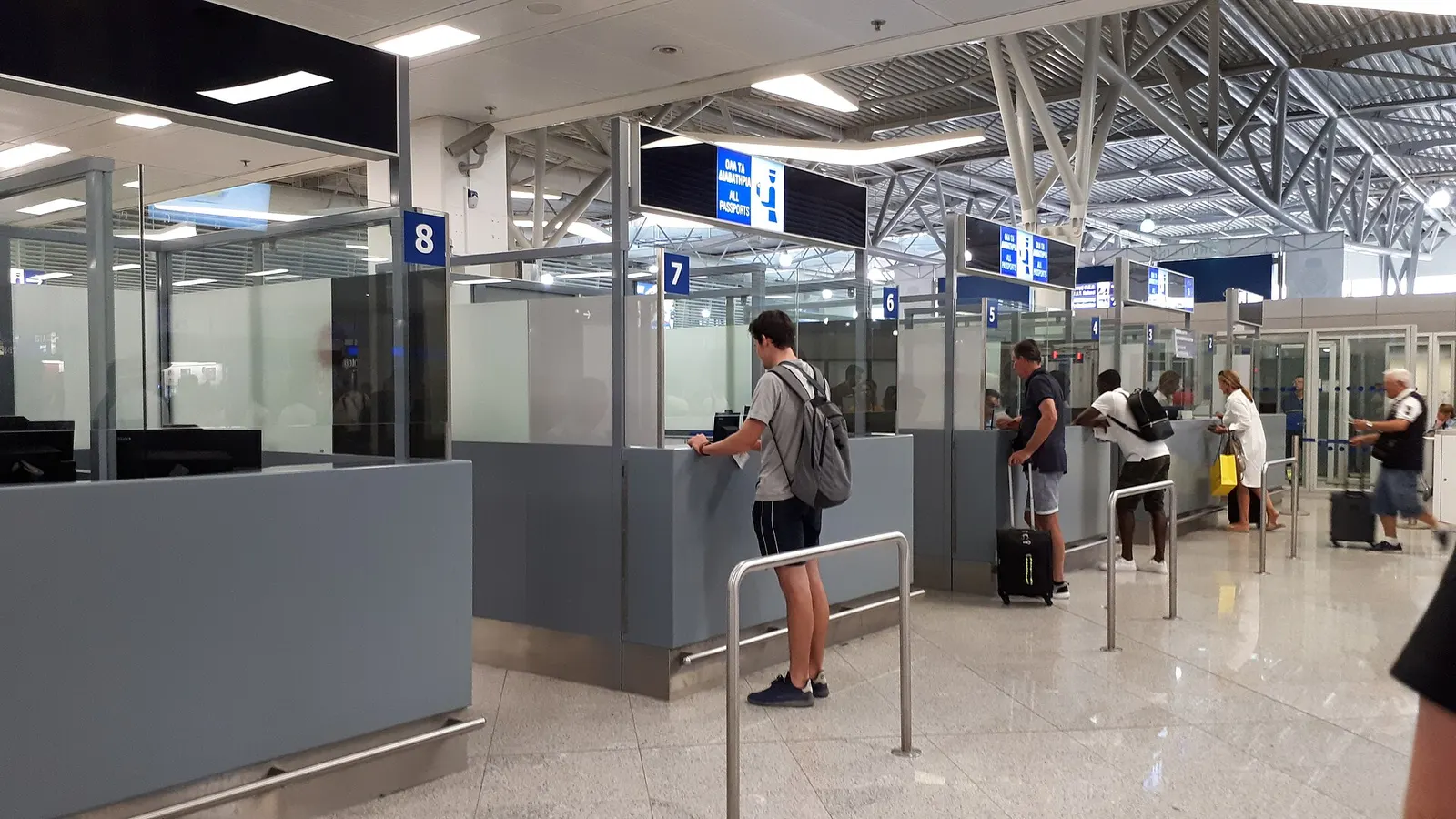 Passengers queuing at passport control booths in the immigration area of Athens International Airport.