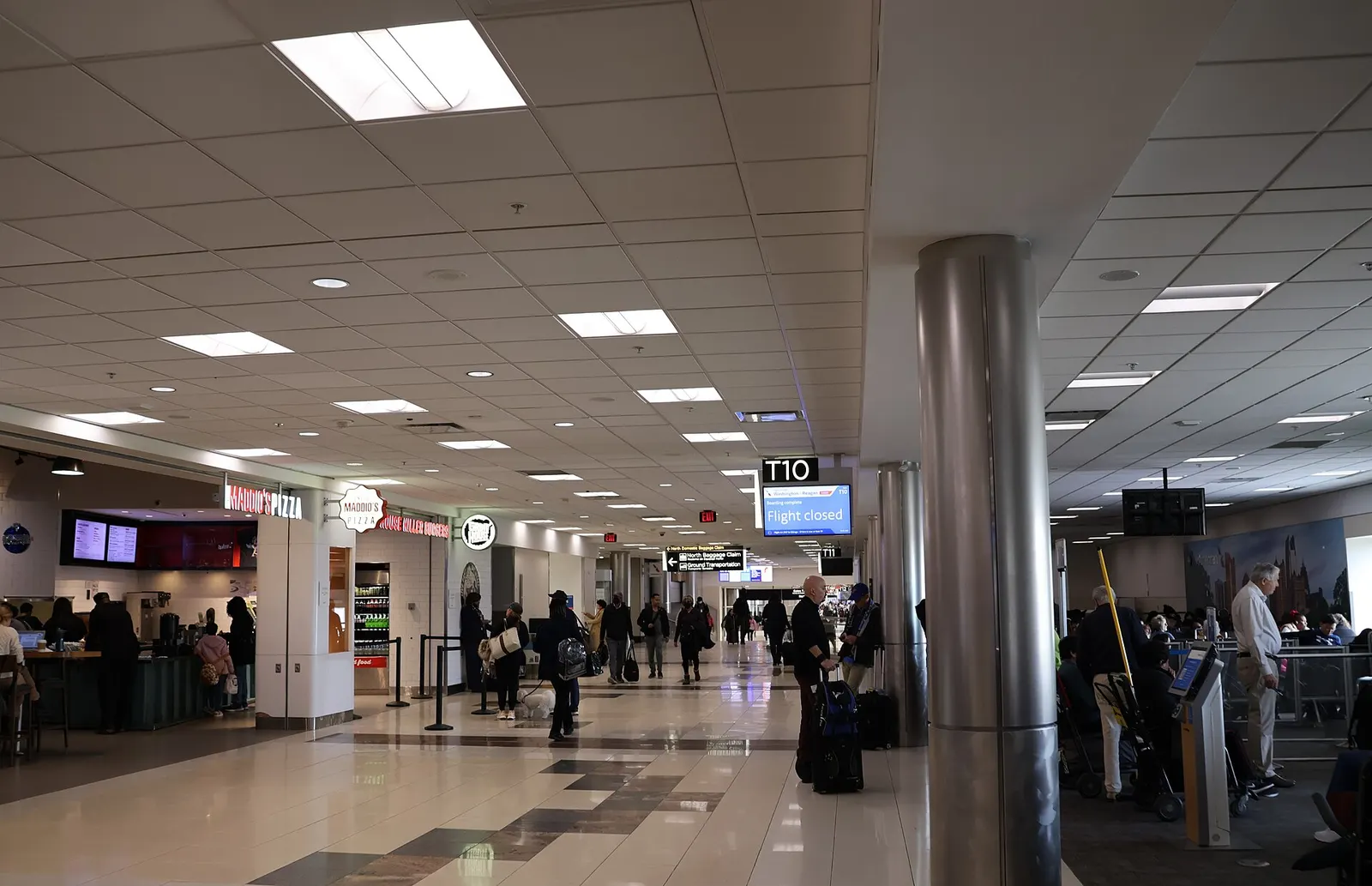 Wide concourse hallway in Terminal T at Hartsfield-Jackson Atlanta International Airport with moving walkways, departure gate signage, and travelers walking toward their gates.