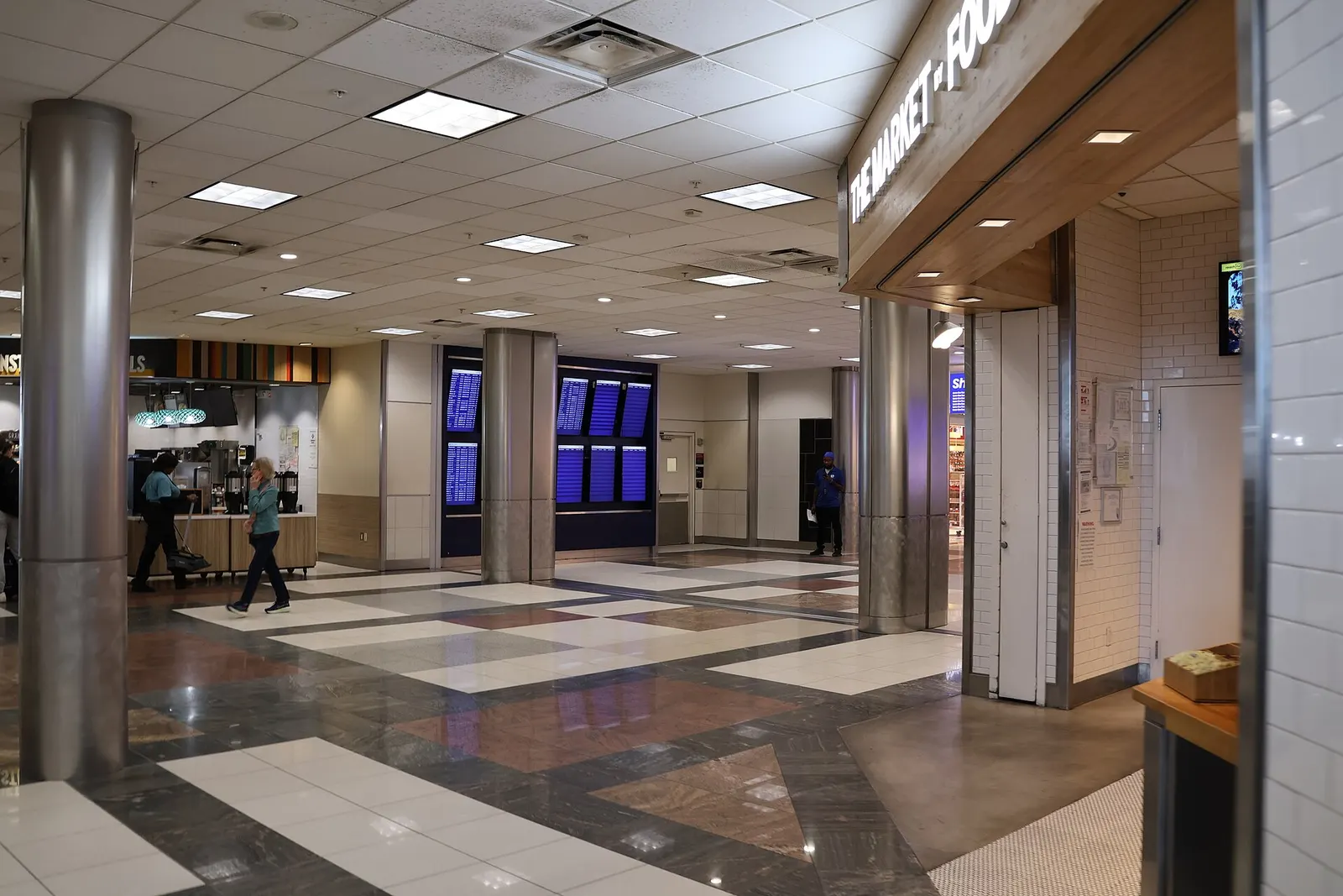 Departures walkway in Concourse D at Hartsfield-Jackson Atlanta International Airport with gate seating areas, airline signage, and travelers heading toward boarding gates.