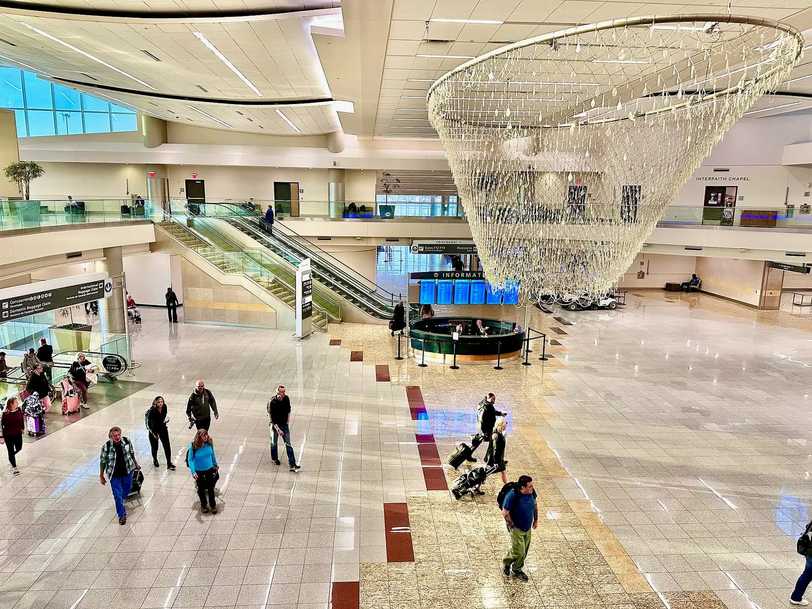 Exterior of the Maynard H. Jackson Jr. International Terminal at Hartsfield-Jackson Atlanta International Airport with a modern glass facade and vehicles on the approach roadway.