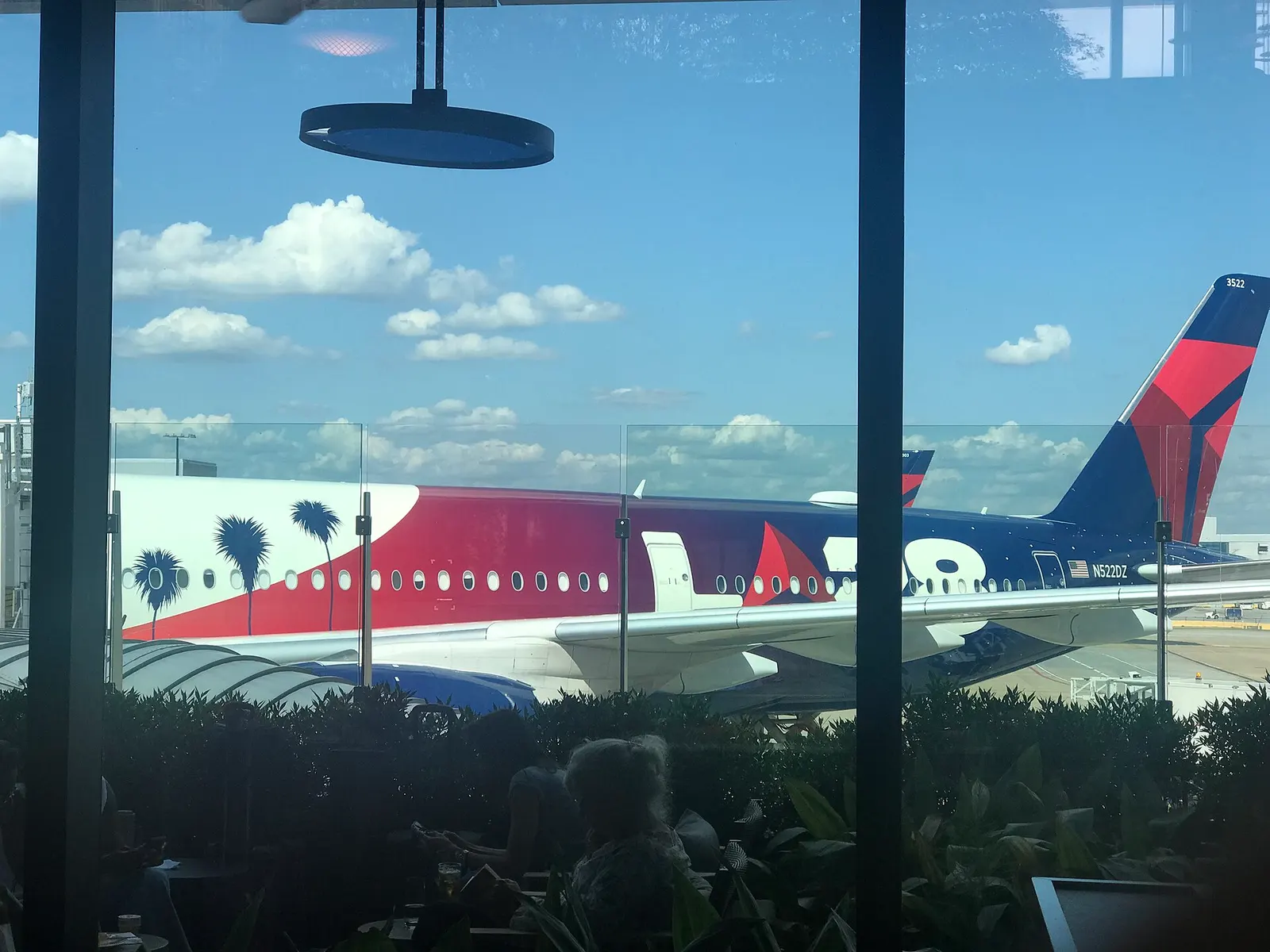 View from inside the Centurion Lounge on Concourse E at Hartsfield-Jackson Atlanta International Airport, looking through lounge windows at an aircraft tail on the ramp.