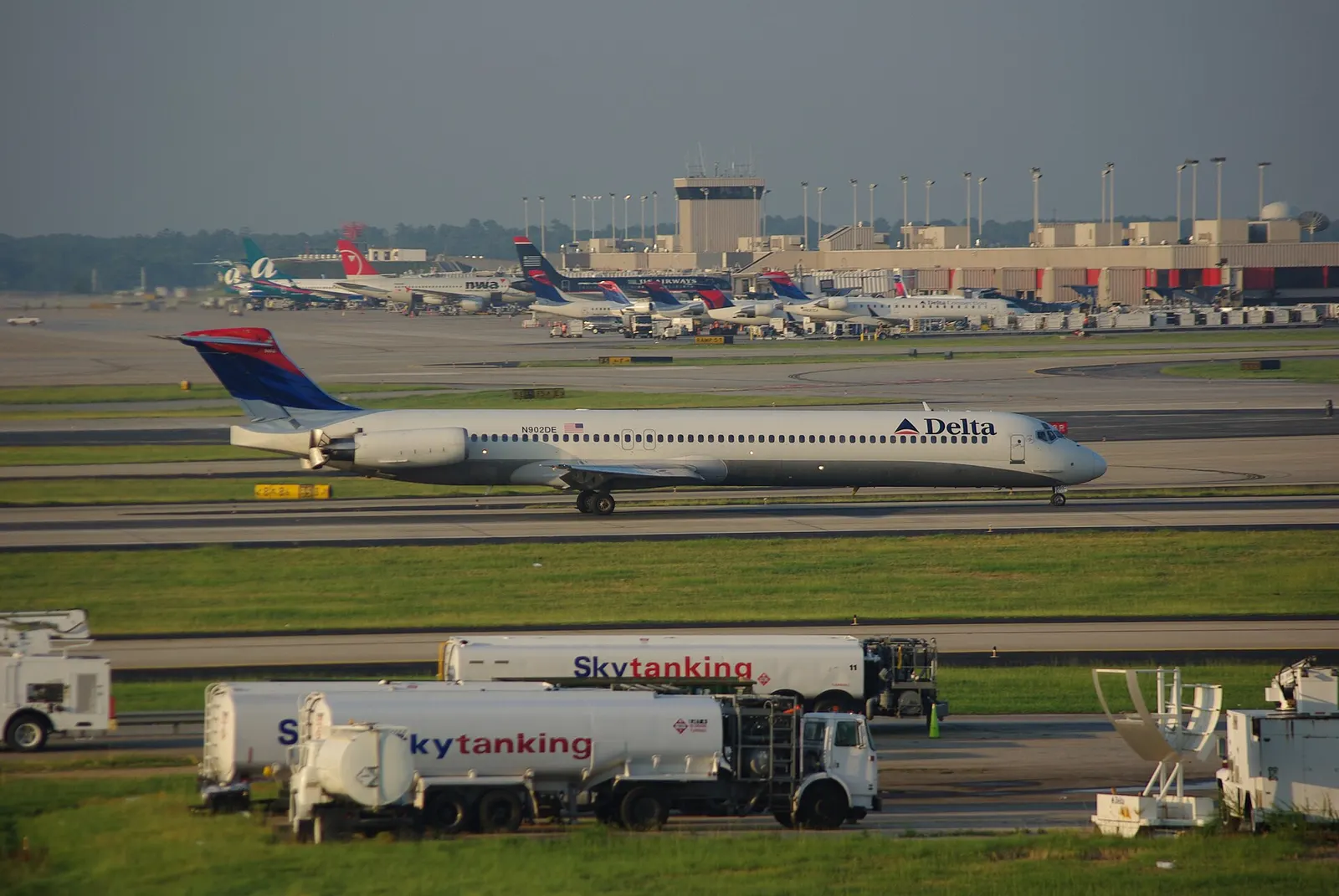 Ground-level view of Hartsfield-Jackson Atlanta International Airport terminals with multiple Delta Air Lines aircraft parked at gates, photographed from a nearby hotel balcony.