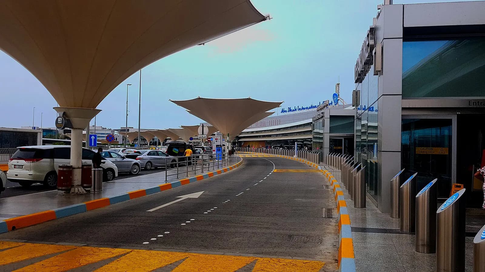A broad exterior view of Abu Dhabi International Airport showing terminal buildings, ramps, and aircraft activity across the airfield in 2022.