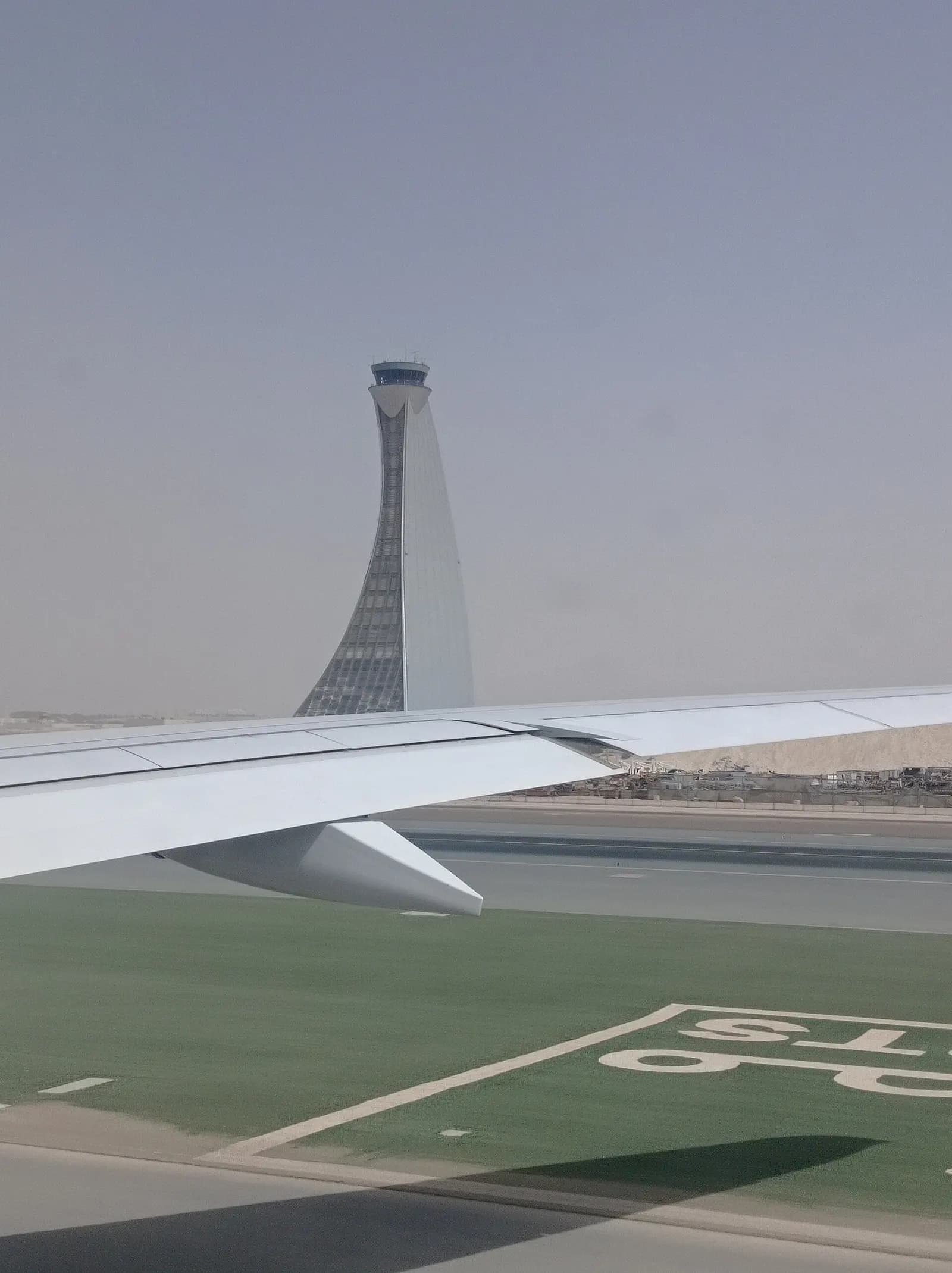 The tall, distinctive air traffic control tower at Abu Dhabi International Airport rising between parallel runways under a clear sky.