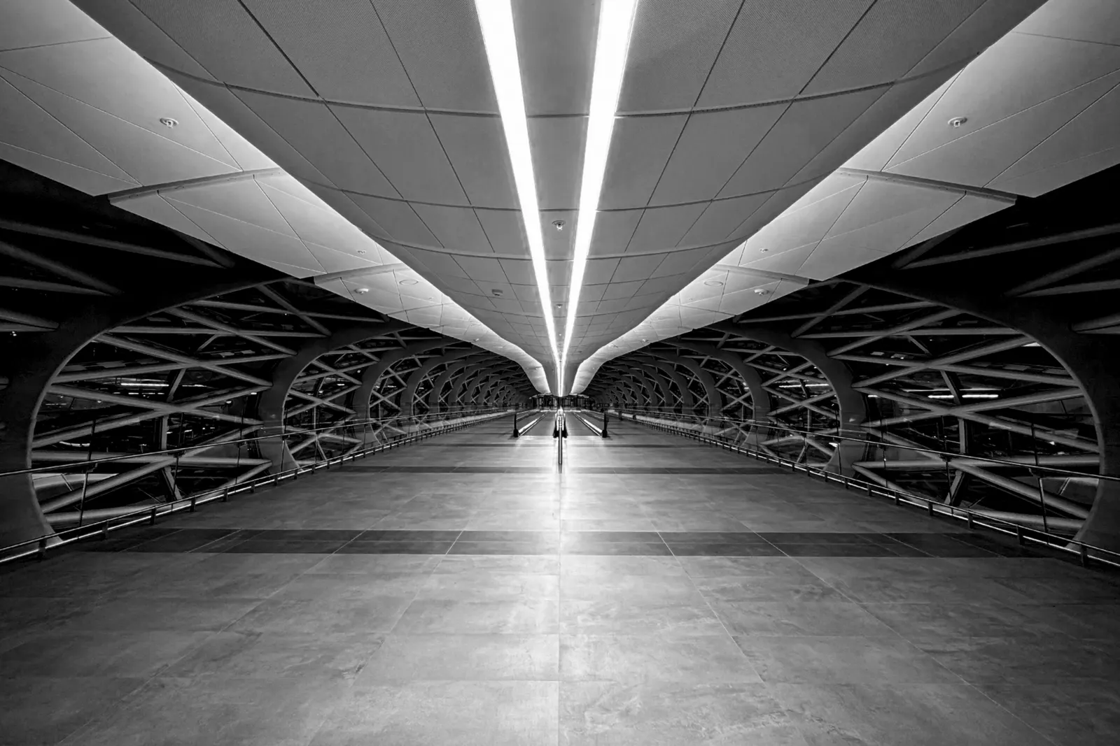 A sweeping, sculptural pedestrian walkway inside the new Terminal A, with curved white ceilings, glass walls, and travelers walking toward the departures hall.