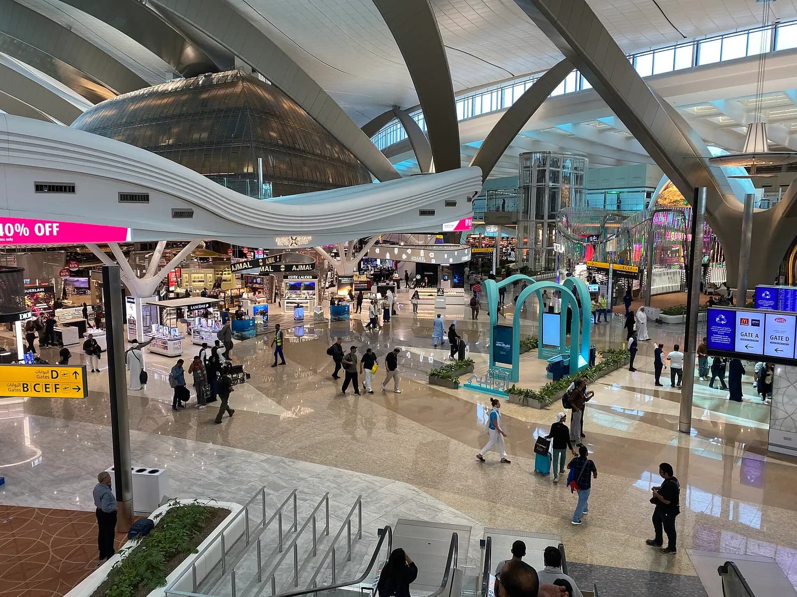 The bright, open main concourse of Terminal A at Zayed International Airport, with high ceilings, natural light, and passengers moving through the departures area.