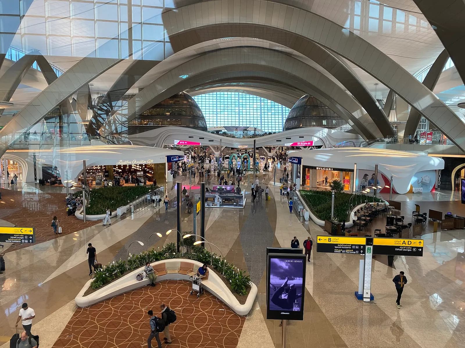 A wide view of Terminal A's airy interior showing check-in counters, signage, and passengers with luggage in the main hall.