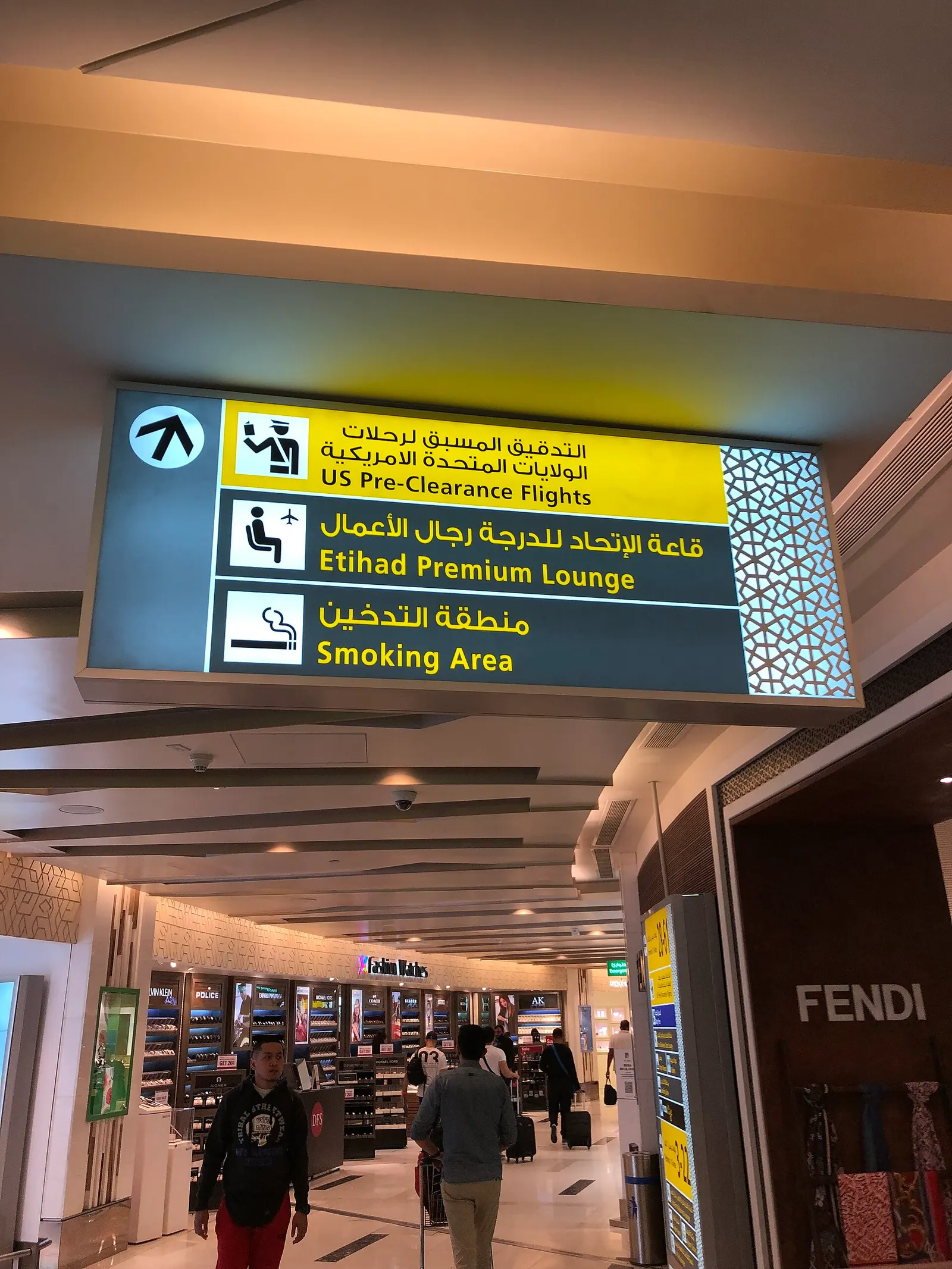 A Terminal 3 direction sign hanging in a corridor beyond the check-in area, with gate and facility icons visible to passengers.