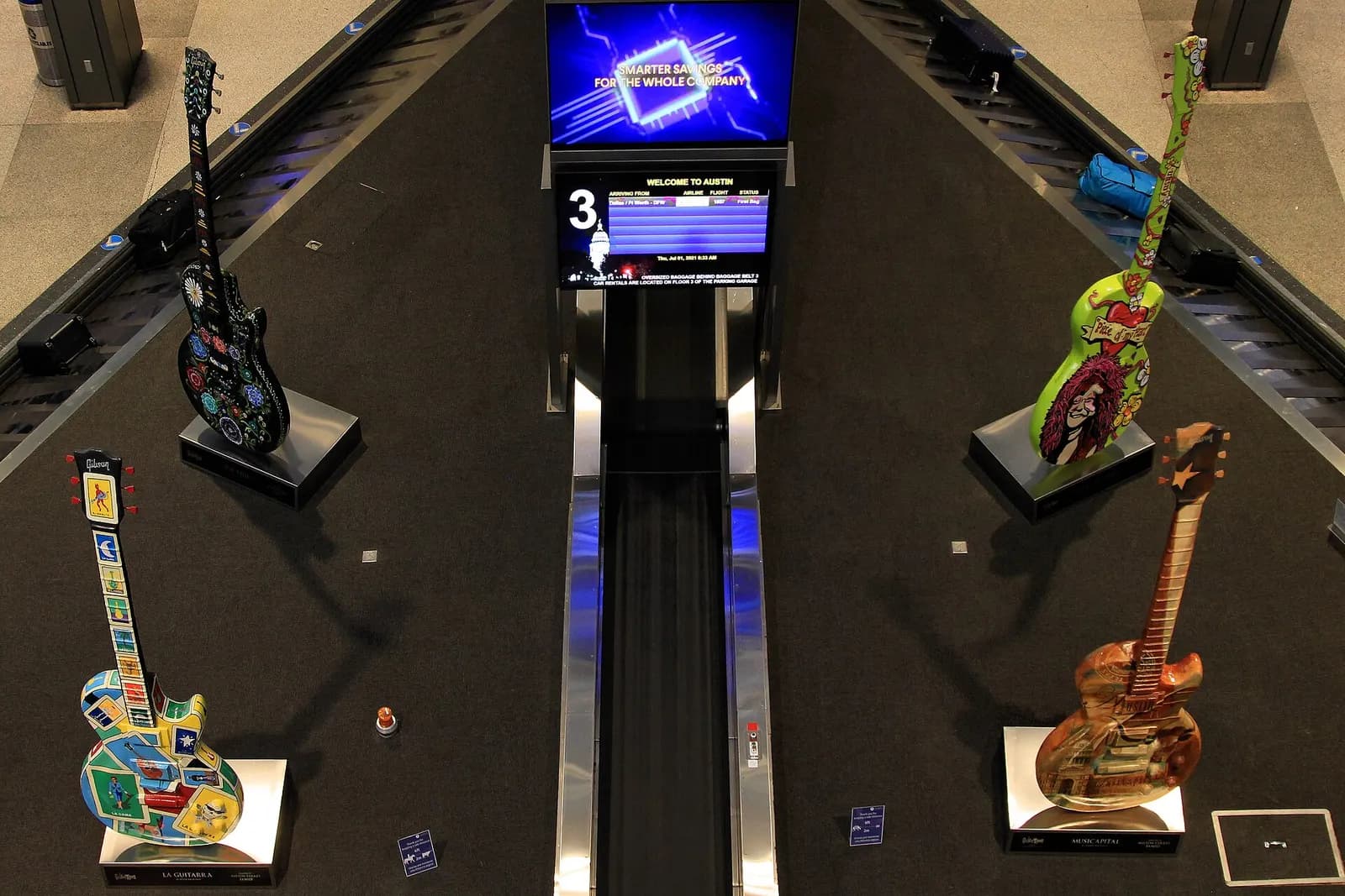 Baggage claim carousel in the Barbara Jordan Terminal backed by a mural promoting Austin as the Live Music Capital of the World.