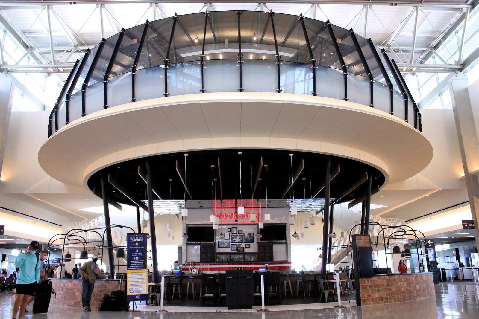 Bright, modern gate area inside the expanded Barbara Jordan Terminal with seating, gate signage, and large windows overlooking the airfield.