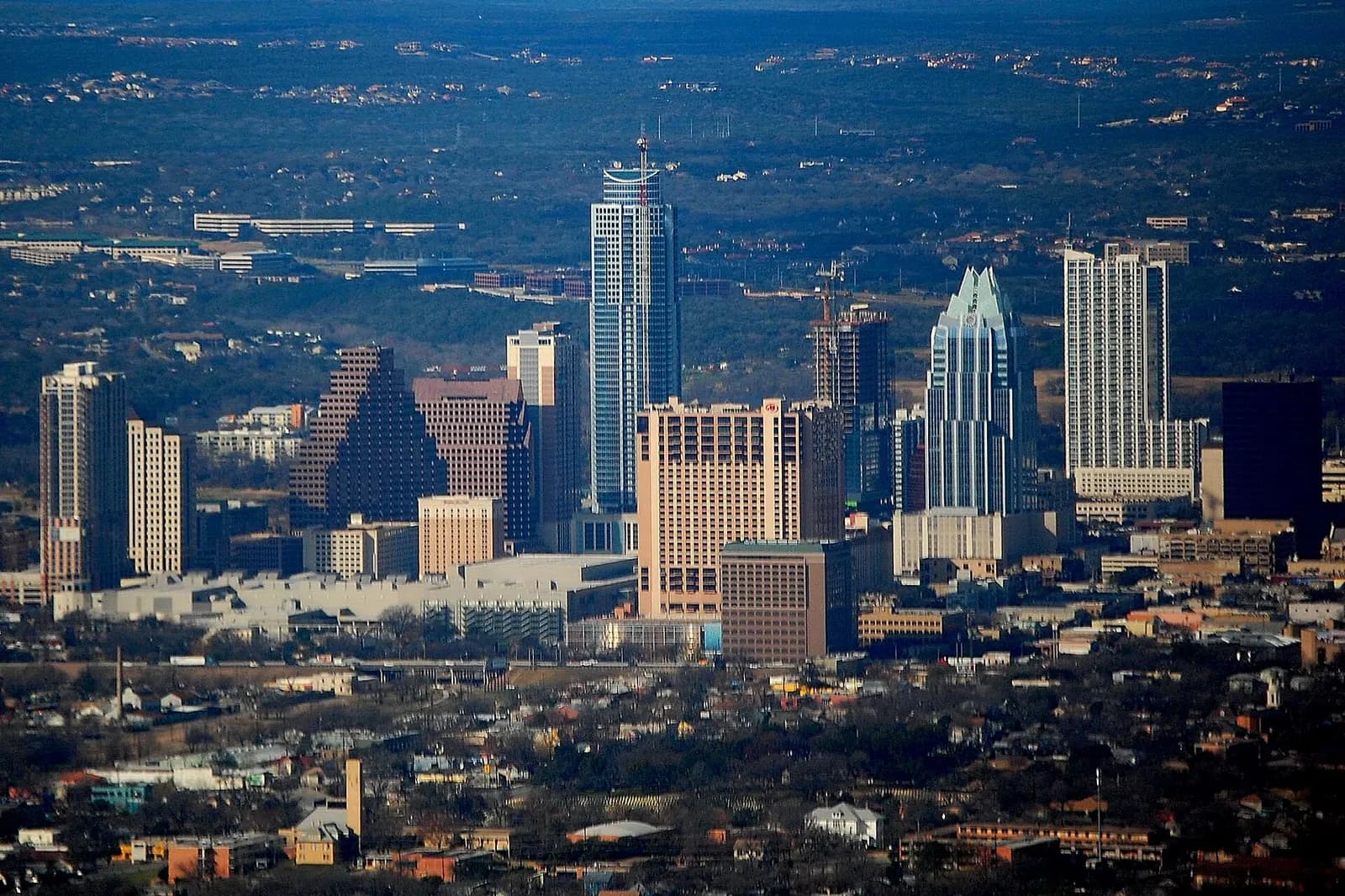 Downtown Austin skyline with high-rise buildings and rolling hills visible from an aircraft on approach to Austin–Bergstrom.