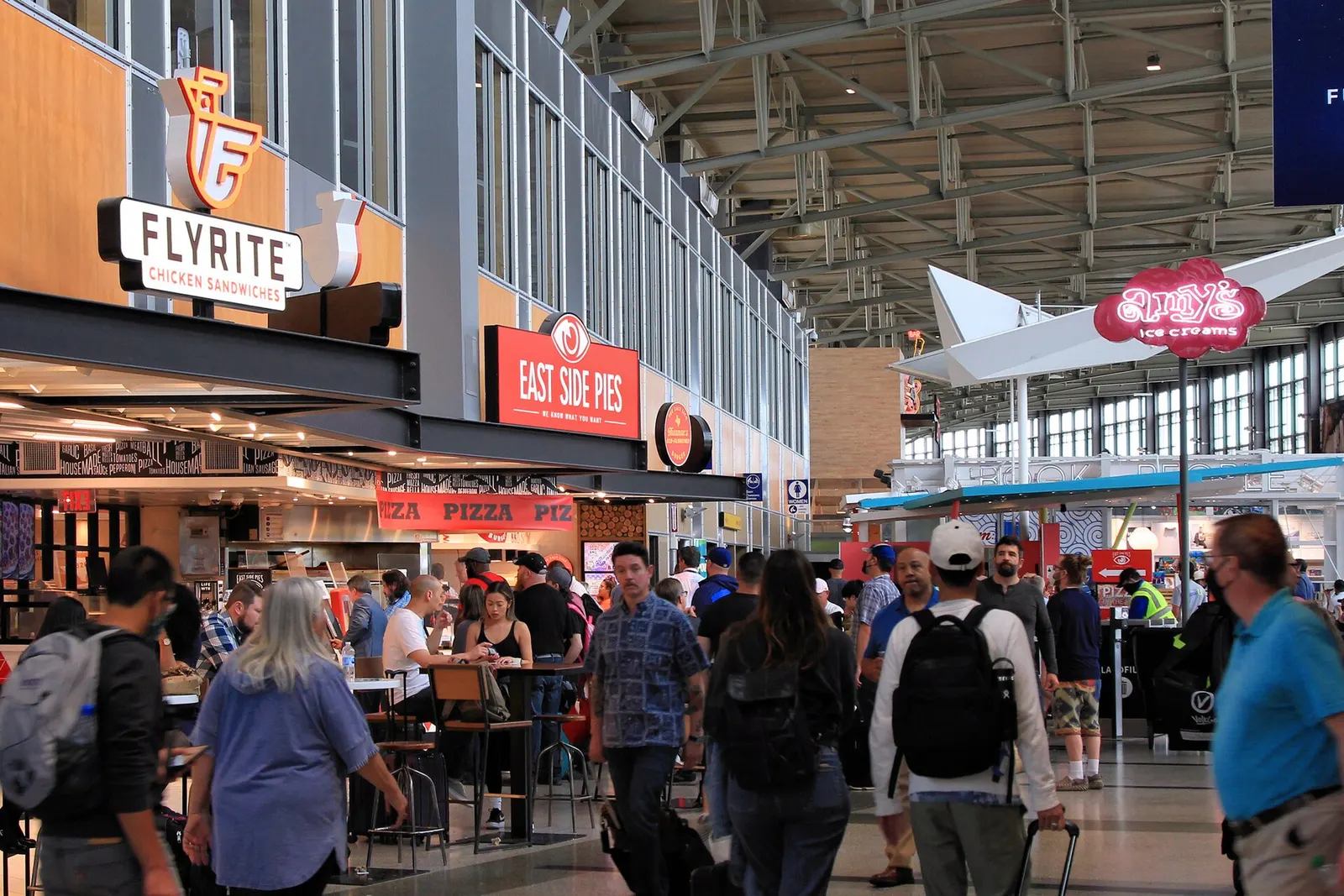Row of local restaurant counters and seating in the Barbara Jordan Terminal dining area near the gates.