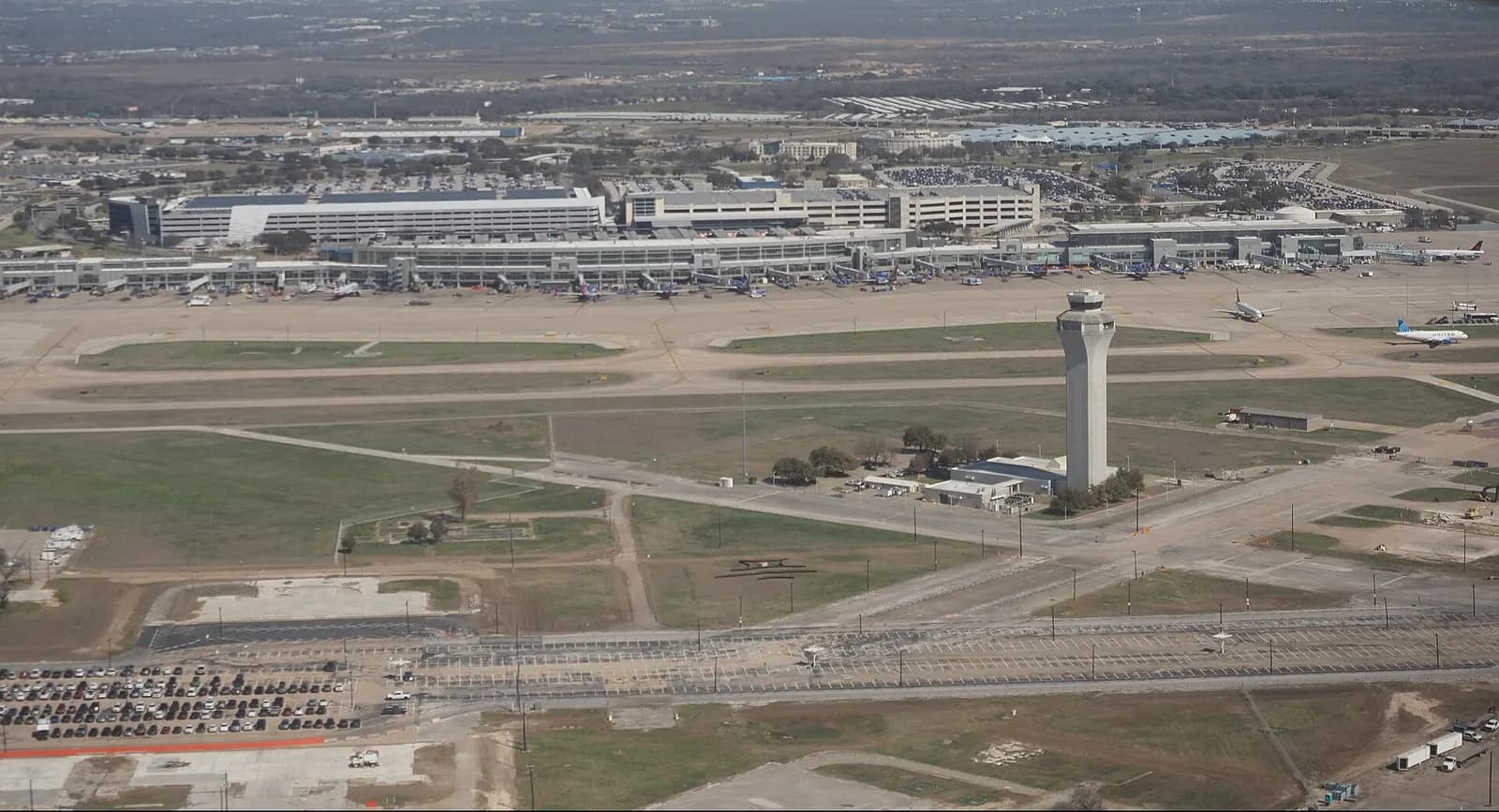 Aerial view of Austin–Bergstrom International Airport showing runways, the air traffic control tower, and the Barbara Jordan passenger terminal.