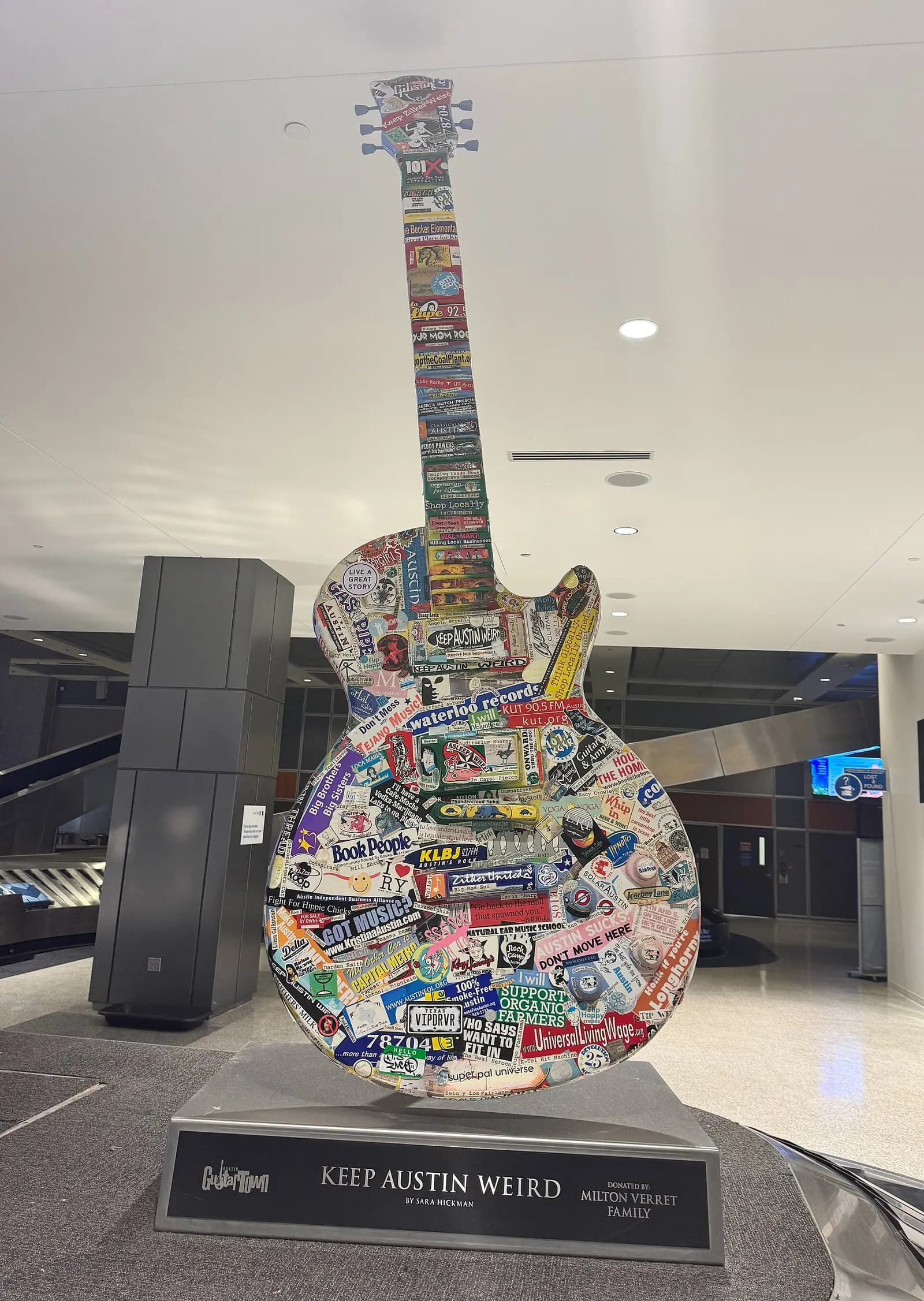 Colorful oversized guitar sculpture with a Keep Austin Weird sign displayed in the Austin airport terminal.