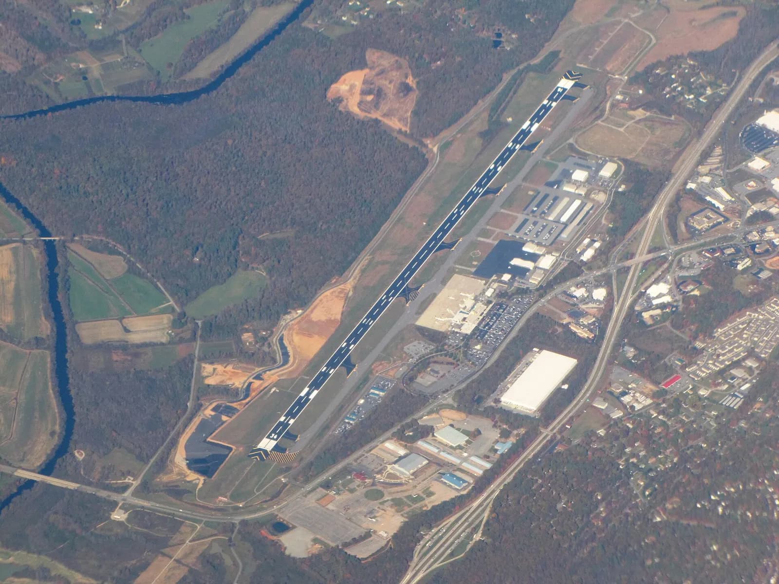 October 2011 aerial of Asheville Regional Airport showing the single civil runway and terminal campus in wooded western North Carolina.