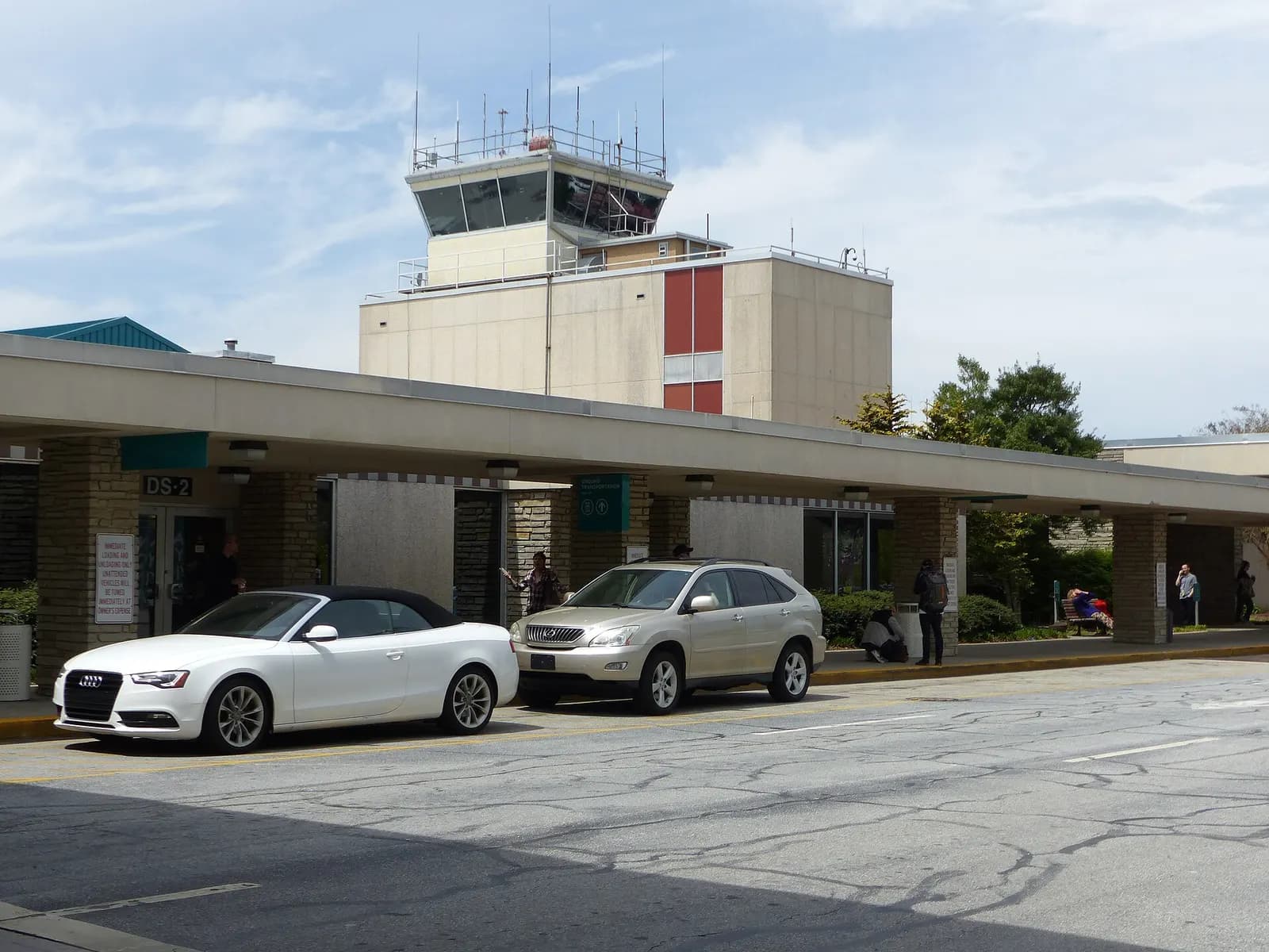 2019 Asheville Regional Airport curb canopy labeled DS-2 with the old civil control tower above two parked cars.