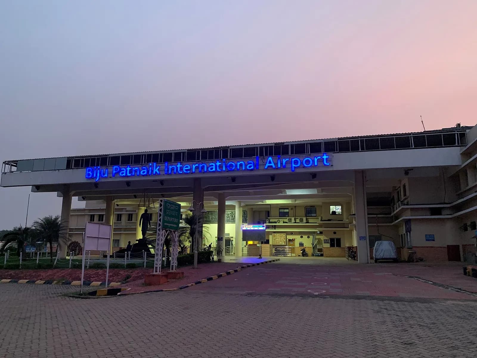 Night entrance canopy of Biju Patnaik International Airport with blue rooftop sign and DEPARTURE board