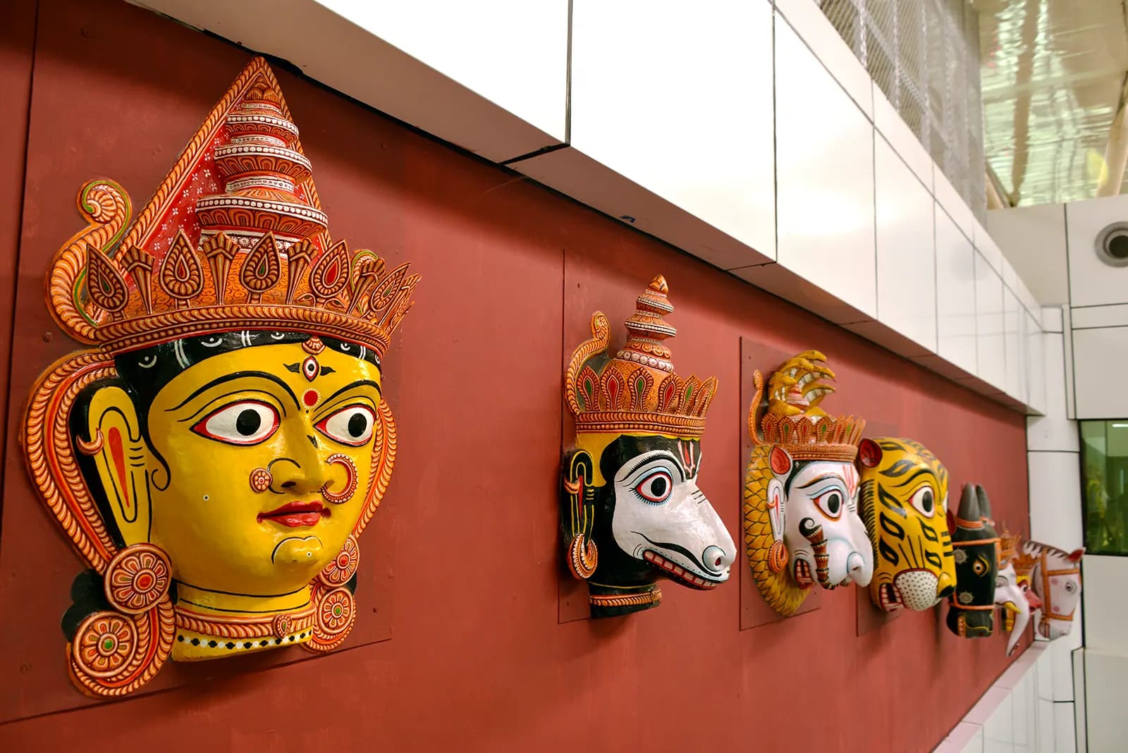 Traditional Odisha folk masks mounted on a terracotta feature wall at Biju Patnaik Airport