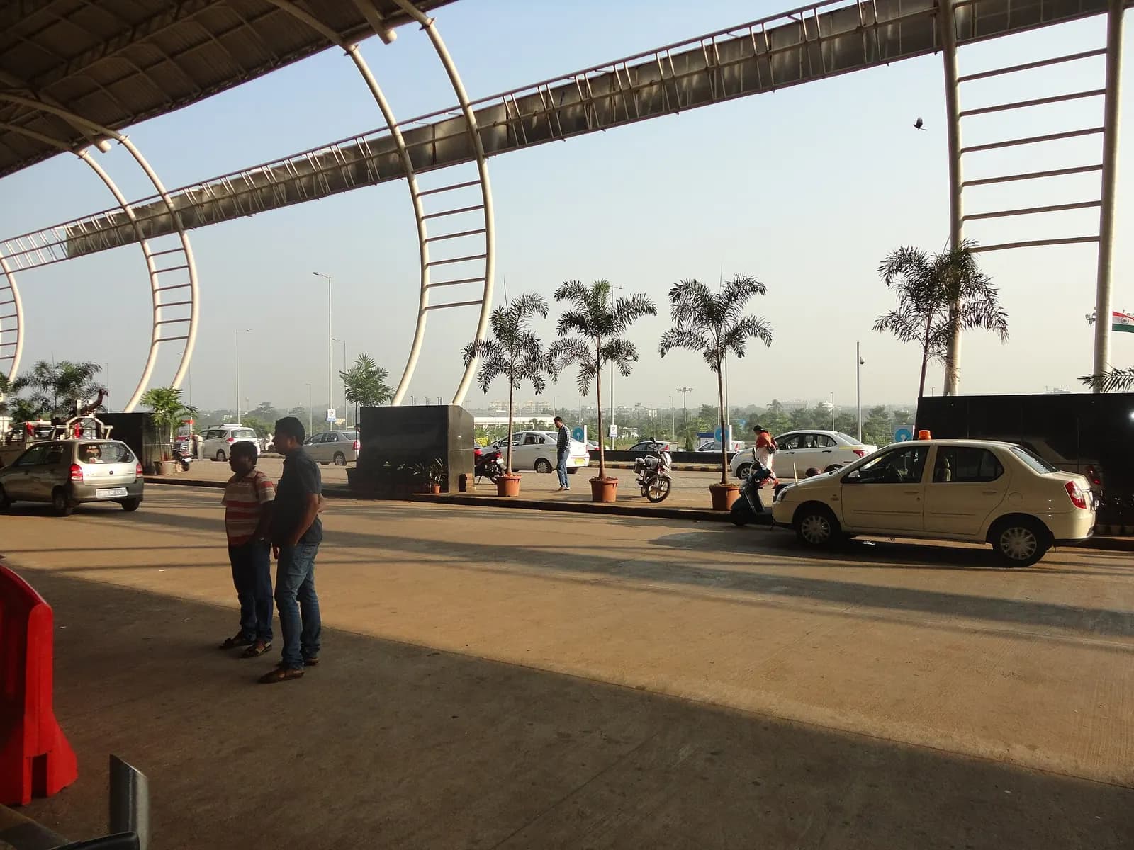 Passenger drop-off kerb under the curved white roof ribs at Biju Patnaik Airport