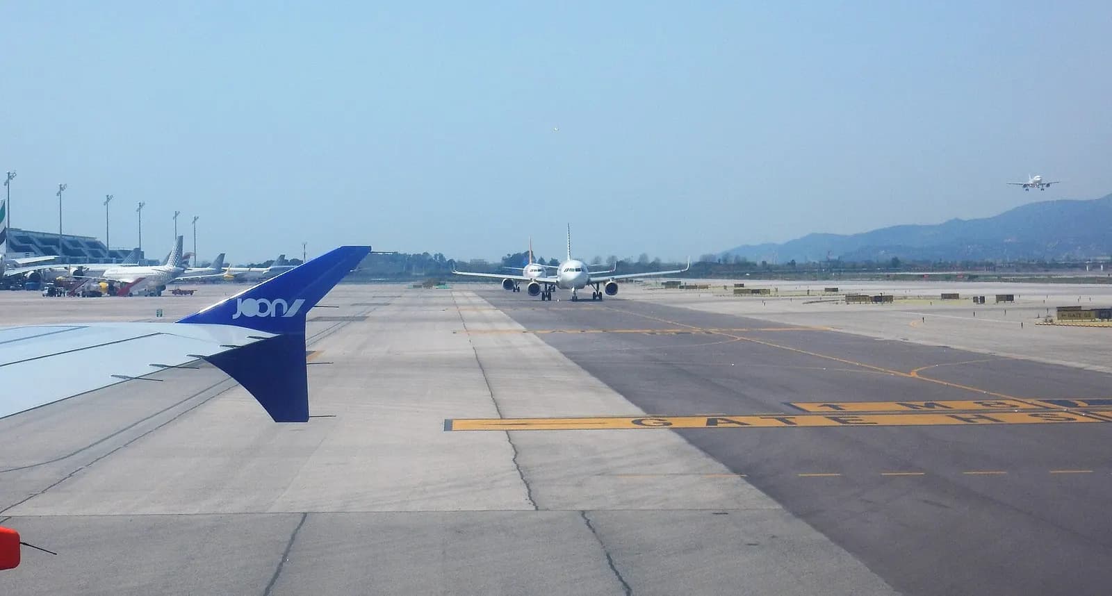 View from an arriving aircraft taxiing on the ramp at Barcelona-El Prat, with multiple planes lined up near the terminals and runways.