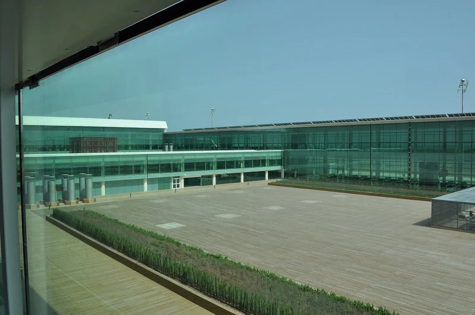 Exterior of Barcelona-El Prat's modern Terminal 1 showing its long curved glass-and-steel facade and wave-like roofline.