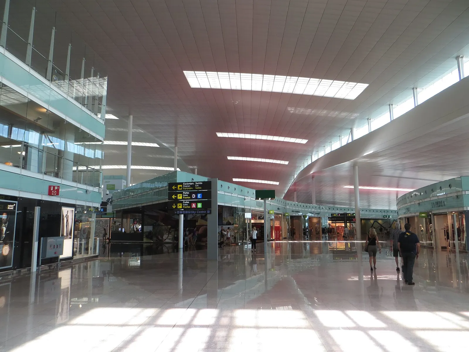 Interior of Terminal 1 at Barcelona-El Prat showing the departures hall, check-in counters, and open multi-level layout.