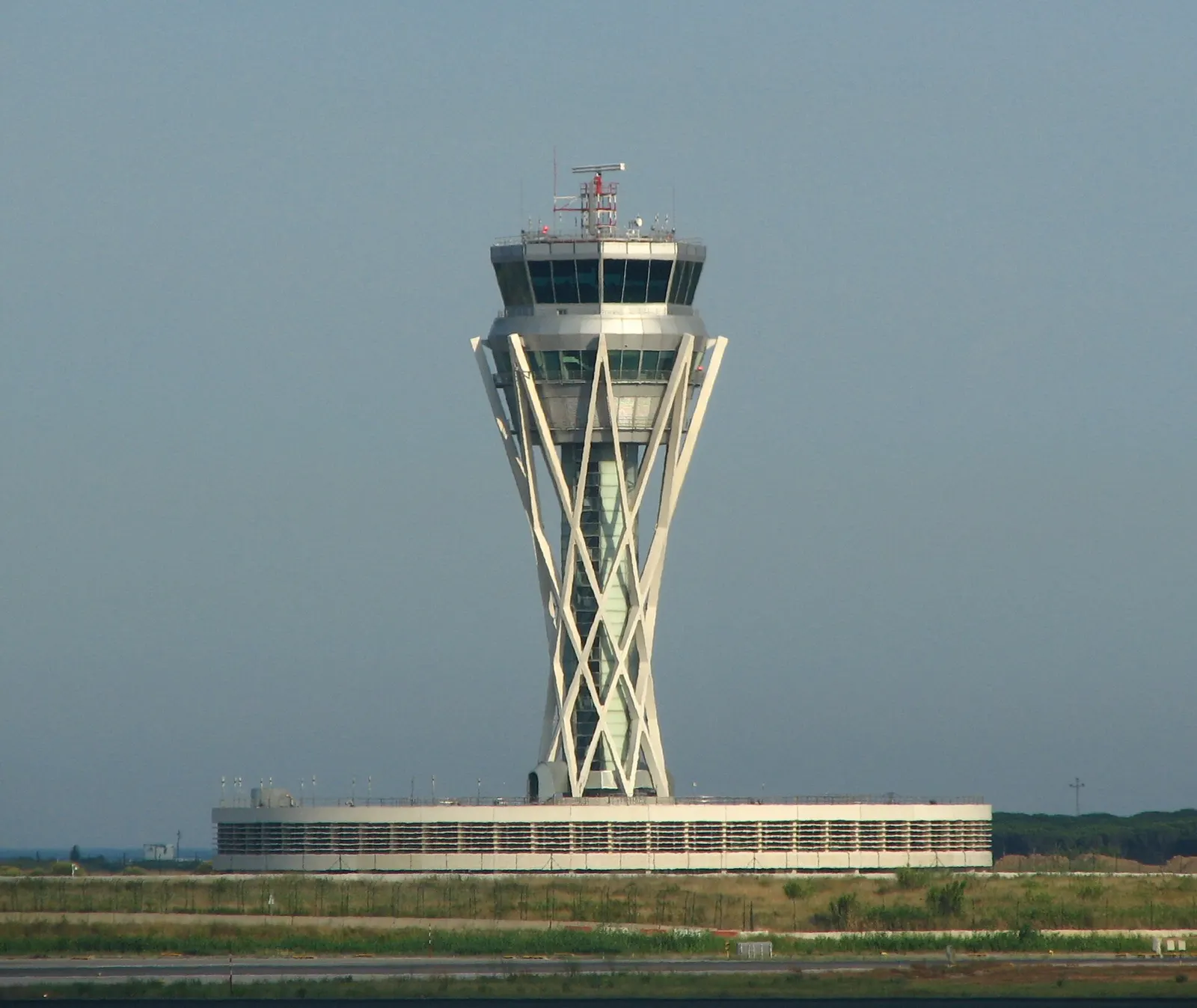 Barcelona-El Prat's distinctive air traffic control tower rising above the airfield on a clear day.