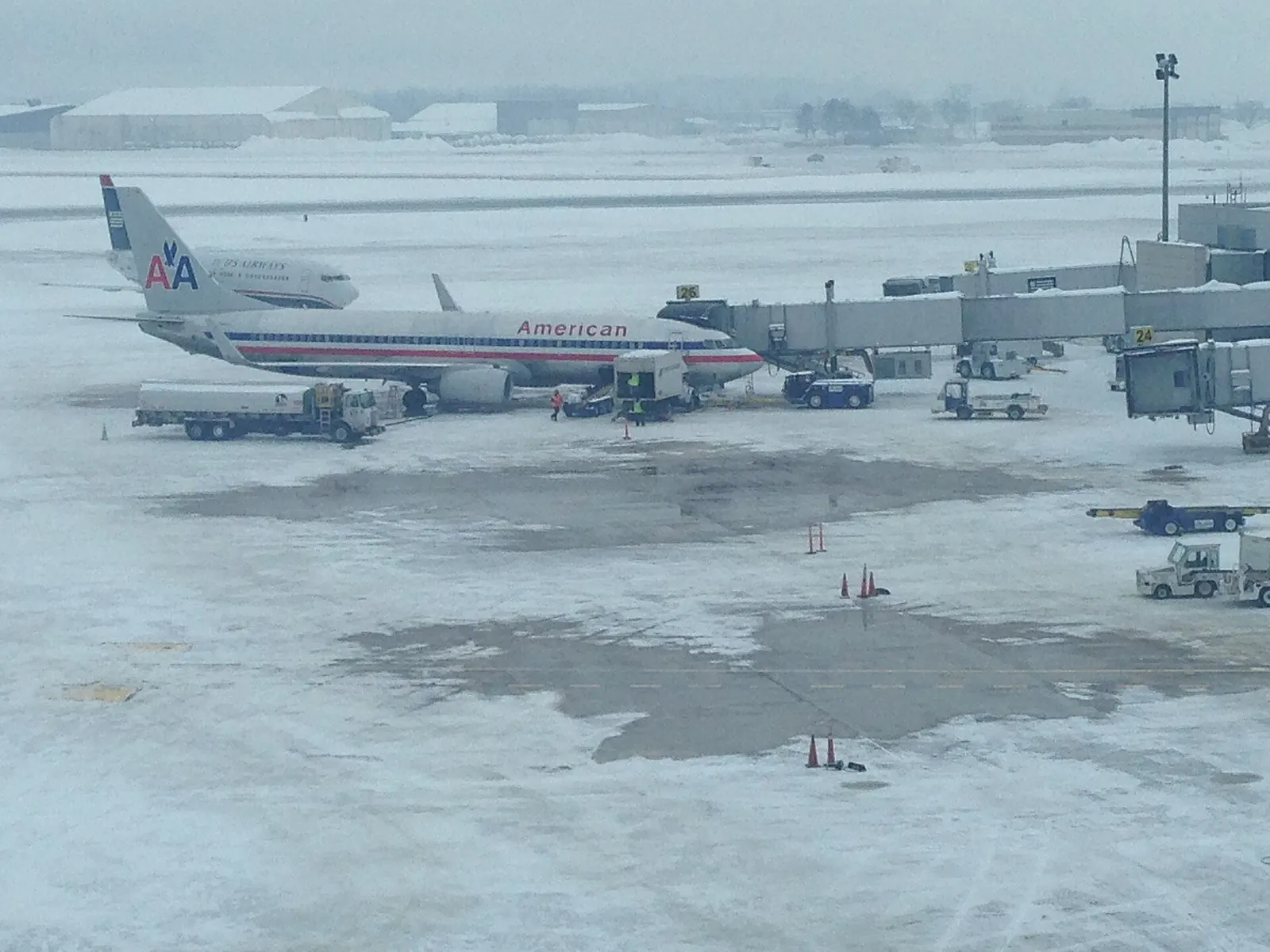 Snow-covered Bradley apron at Gates 24 and 26 with an American jet on the bridge