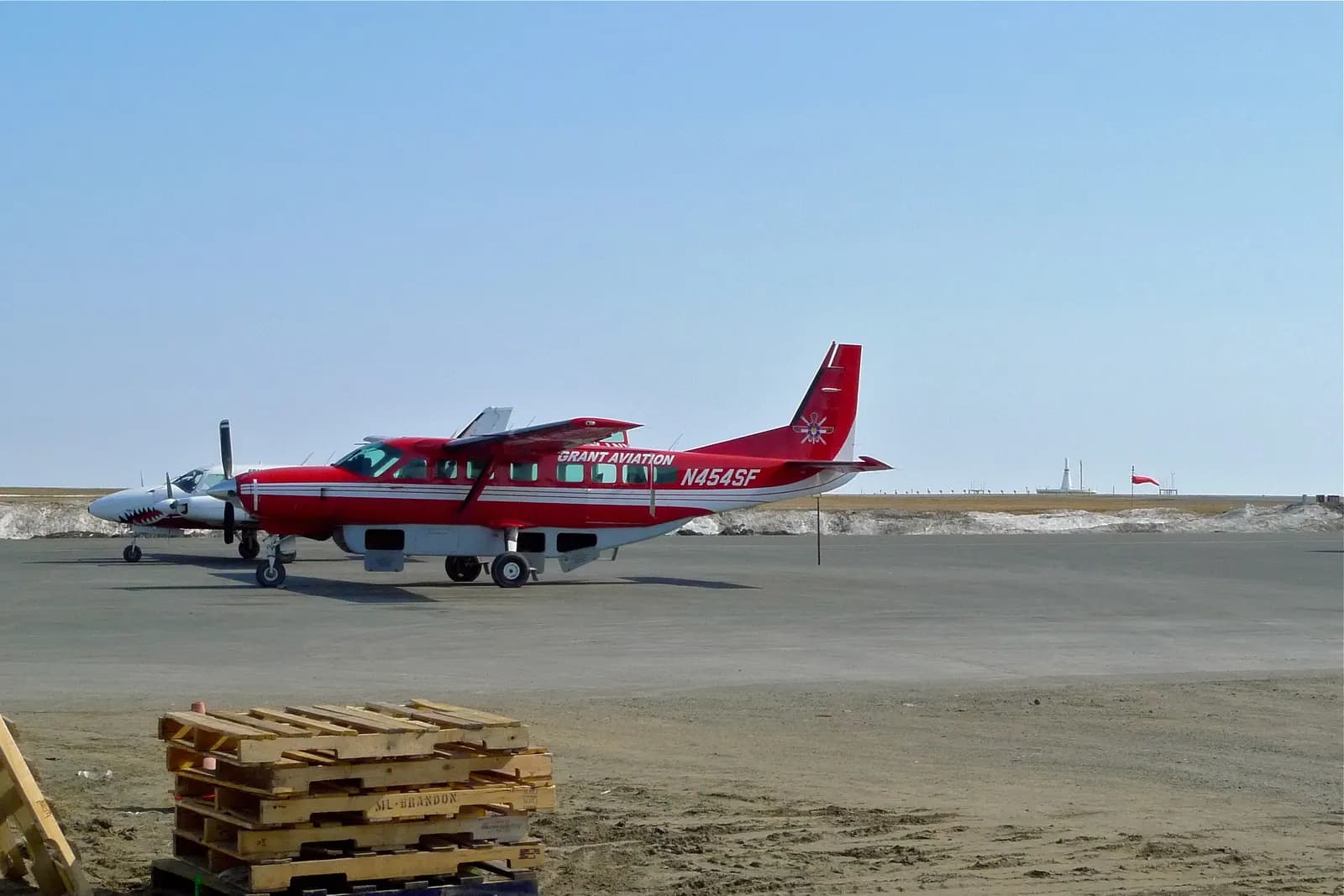 Small commuter airplanes parked on the Bethel Airport ramp with the passenger campus in the background.