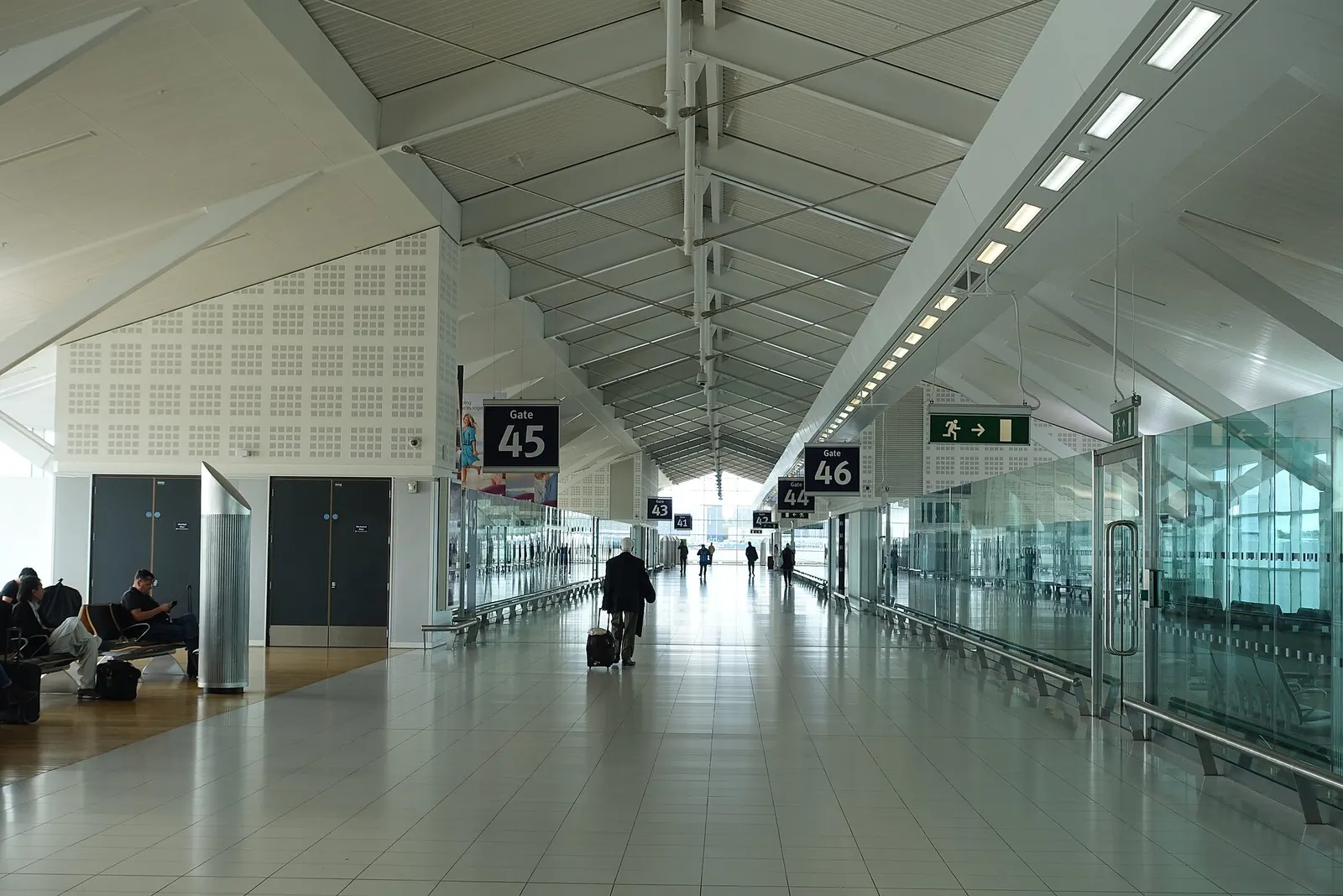 A row of departure gates in Birmingham Airport's terminal, with seating areas and gate signage along the concourse.