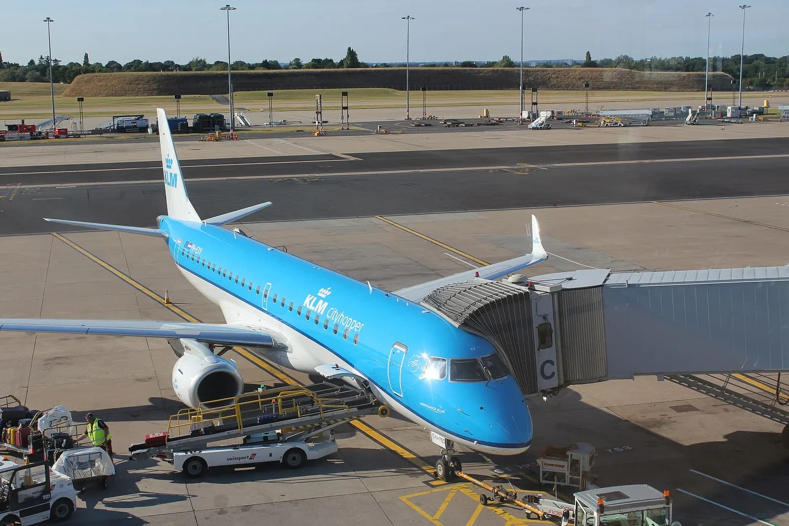 A KLM aircraft parked at a gate at Terminal 1, Birmingham Airport, connected to the terminal by jet bridges.