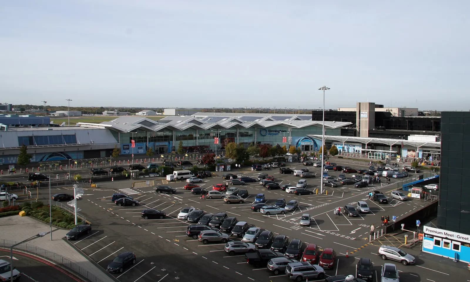 The main terminal buildings at Birmingham Airport seen from the approach road, with glass facades and covered walkways in front.