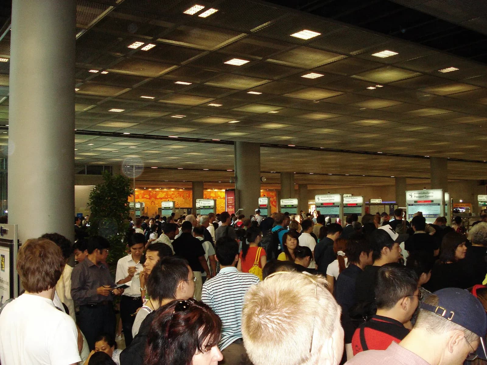 Immigration and passport-control booths lining a wide arrivals corridor, with queue lanes and overhead signage at Suvarnabhumi Airport.