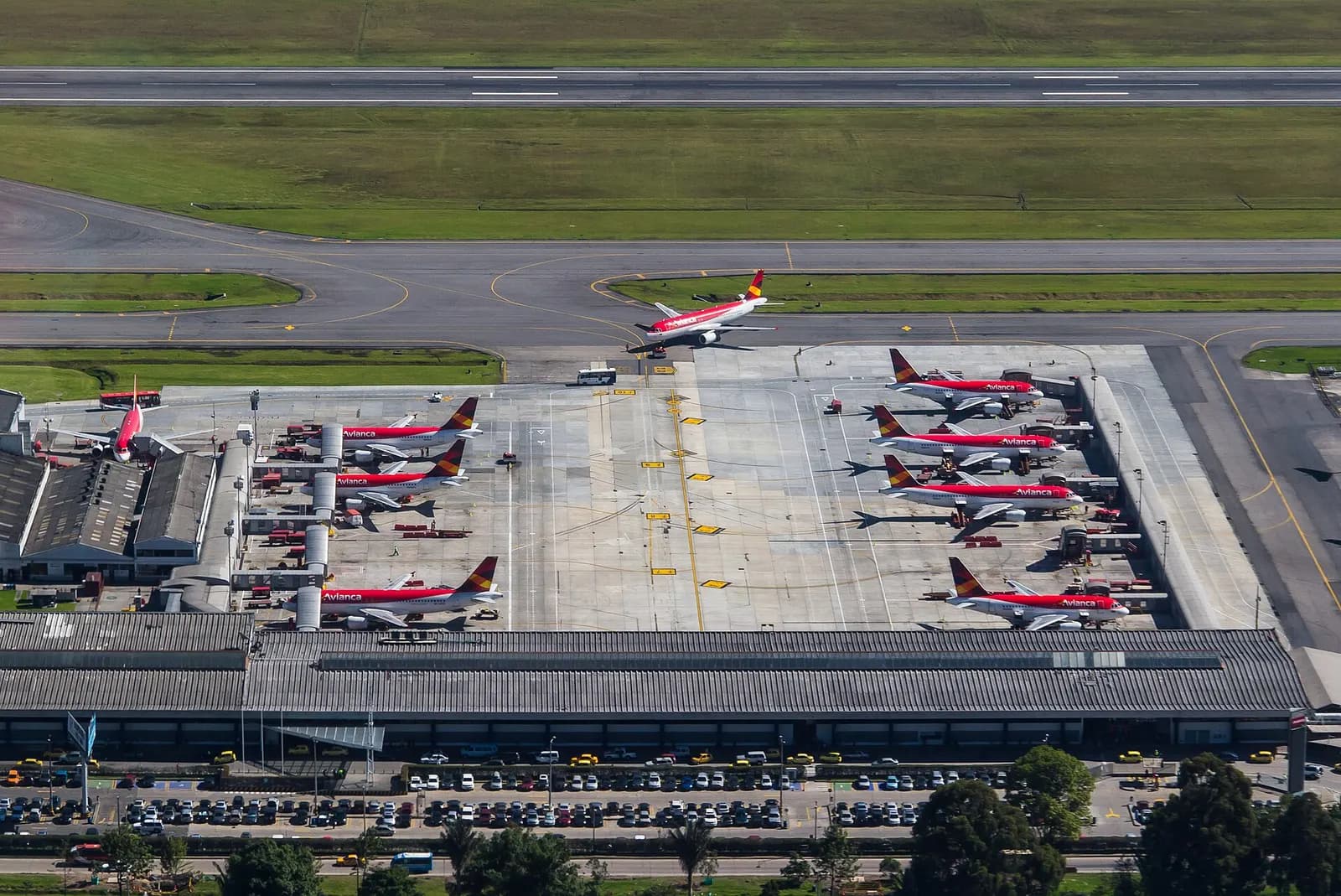 An aerial photo shows the separate Puente Aéreo terminal beside the main apron, parking lots, and multiple Avianca aircraft at adjacent gates.