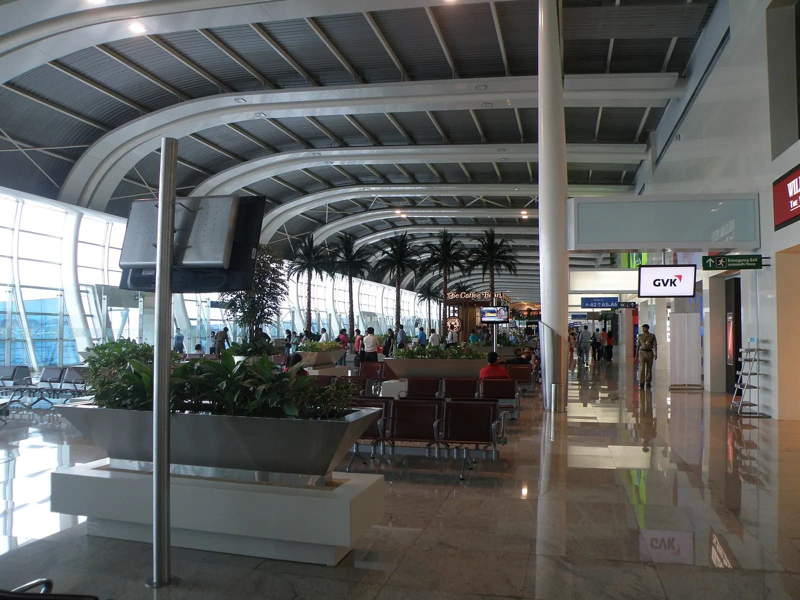 Travelers move through the domestic departure hall at Terminal 1C past check-in counters, signage, and open concourse space.